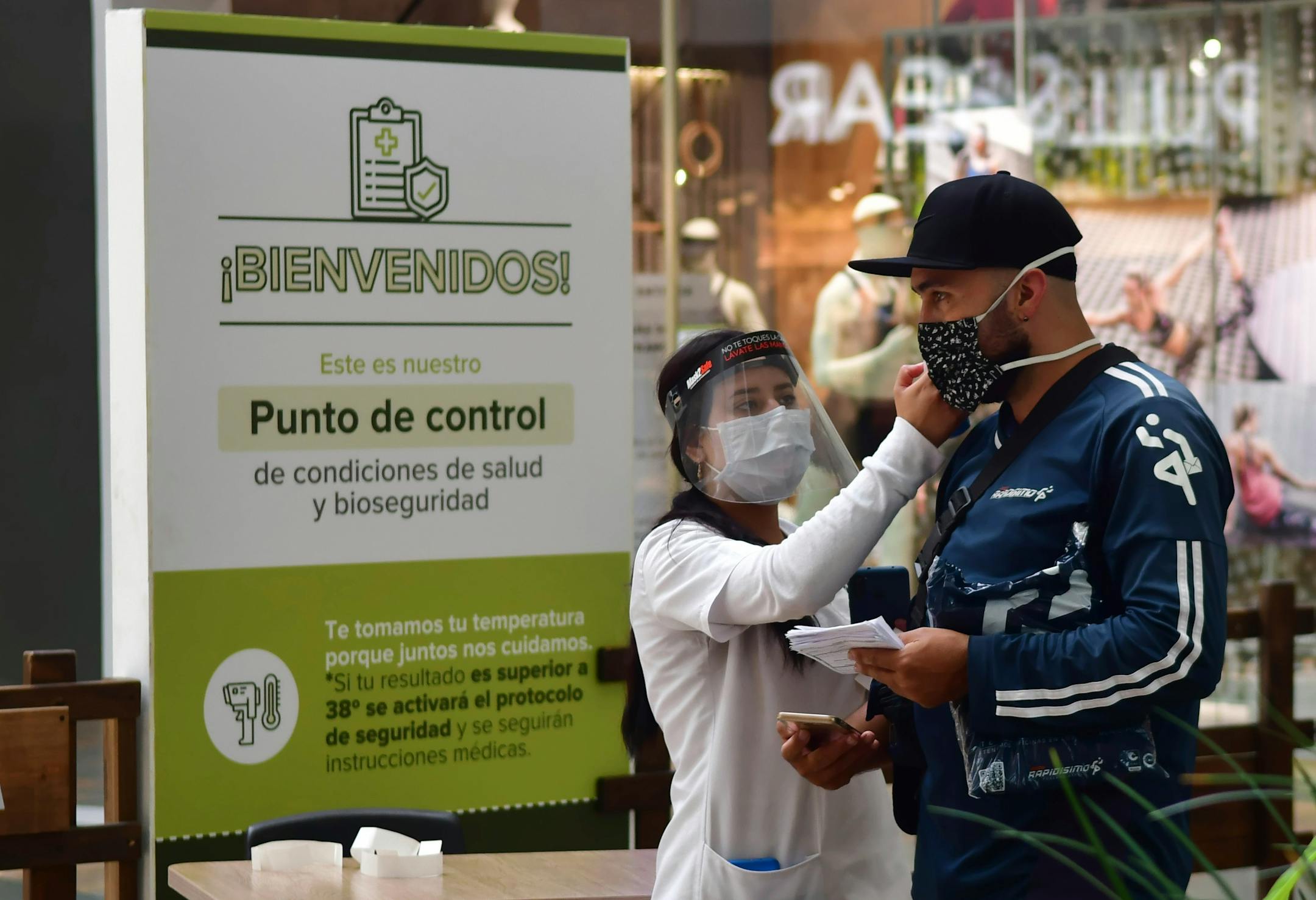 In this June 9, 2020 photo, a nurse measures the body temperature of a shopper at the El Tesoro mall, amid the new coronavirus pandemic, in Medellin, Colombia.