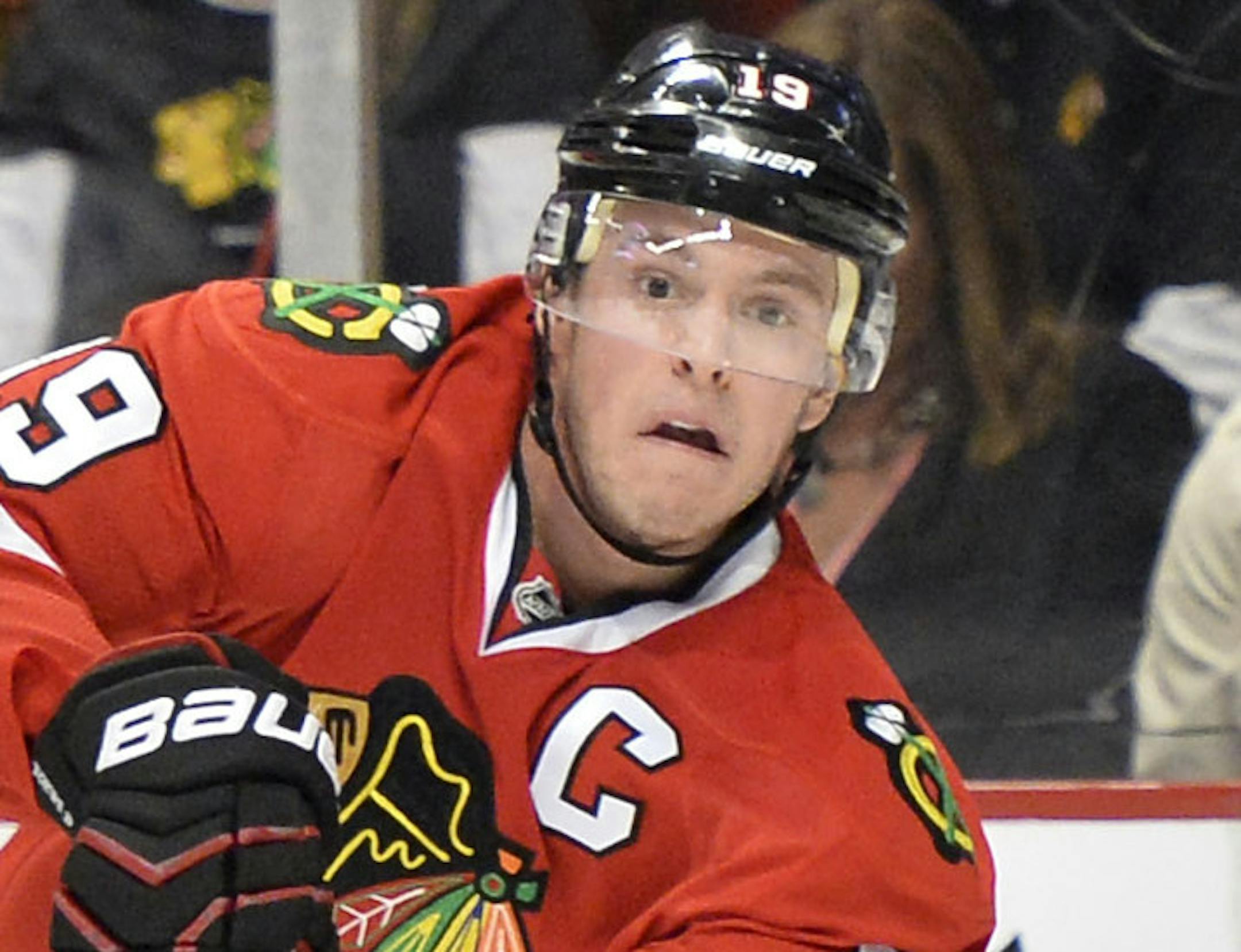 Chicago Blackhawks' Jonathan Toews, right, passes the puck as Calgary Flames' Dennis Wideman defends during the second period of an NHL hockey game, Friday, April 26, 2013 in Chicago. (AP Photo/Brian Kersey)