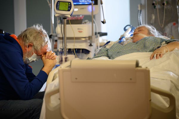 Terry Reynolds, of Plymouth, prayed Wednesday at the bedside of his wife, Carolyn, critically ill with COVID-19 in the South Seven Intensive Care Unit