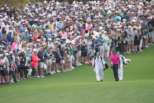 Tiger Woods heads up the fairway after hitting his tee shot on the first hole.