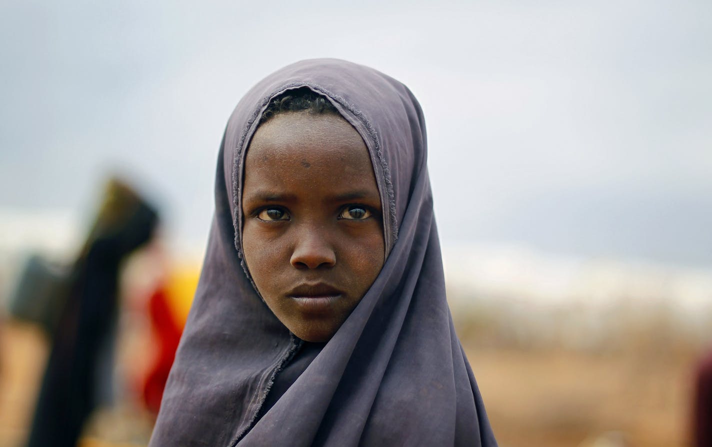 A Somali girl waits to collect water at the UNHCR's Ifo Extension camp, outside Dadaab, eastern Kenya, 100 kilometers (62 miles) from the Somali border, Wednesday, Aug. 10, 2011. The Dadaab refugee camp - the largest in the world - was built for 90,000 people. The current population is over 400,000 with thousands of new arrivals crammed into areas outside the refugee camp, waiting to be formally admitted. (AP Photo/Jerome Delay)