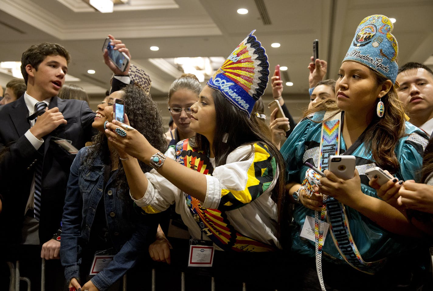 Shasta Dazen, 21, center, of Whiteriver, Ariz., who is the 53rd Miss Indian Arizona, and Deandra Antonio, 17, right, both of the White Mountain Apache Nation and who serve on the White Mountain Apache youth council, vie for a glimpse of first lady Michelle Obama, after she spoke at the first White House Tribal Youth Gathering, Thursday, July 9, 2015 in Washington. First lady Michelle Obama on Thursday told hundreds of Native American youth that they are all precious and sacred and that &#xec;eac