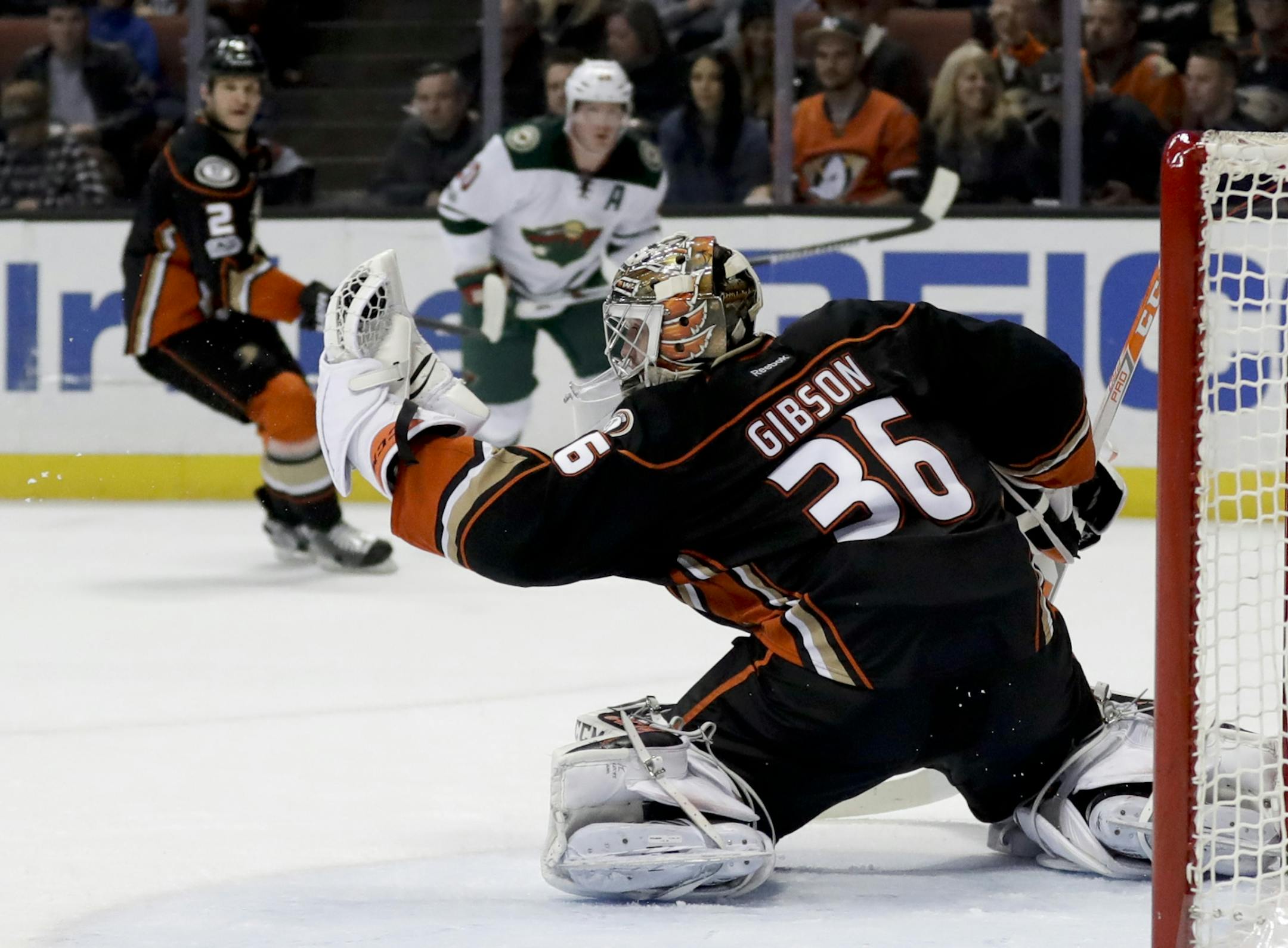 Anaheim Ducks goalie John Gibson, right, blocks a shot by Minnesota Wild defenseman Ryan Suter as defenseman Kevin Bieksa, left, looks on during the first period of an NHL hockey game in Anaheim, Calif., Sunday, Jan. 8, 2017.