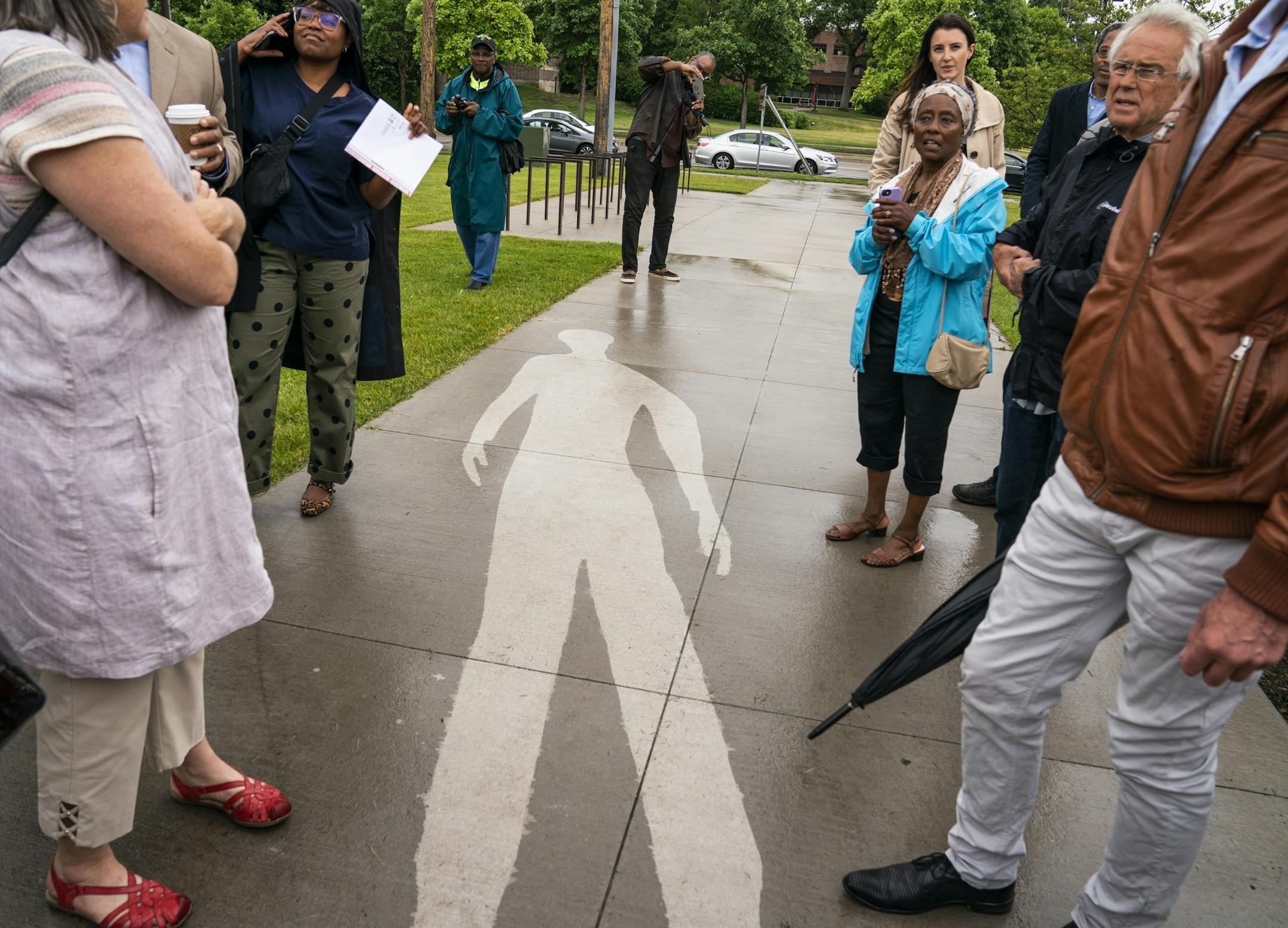 People explore the piece "Kirk Washington, Jr." which only reveals itself when it rains, from the series "Shadows at the Crossroads" during the public unveiling.
