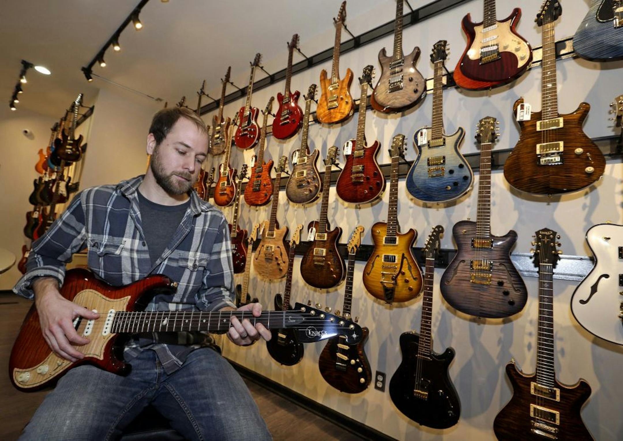 Noah Saydel, marketing manager for Distinctive Guitar, tries out a Knaggs Severn, a high end boutique guitar, on Jan. 28, 2015 in Milwaukee, Wis. Some of their pricey electric guitars sell for $2,500 to $7,500 and are made by small builders. It's a niche that has expanded greatly over the last several years.