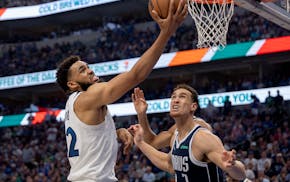 The Wolves' Karl Anthony Towns puts up a shot at the rim against the Mavericks' Dwight Powell during the second quarter Sunday night in Dallas.