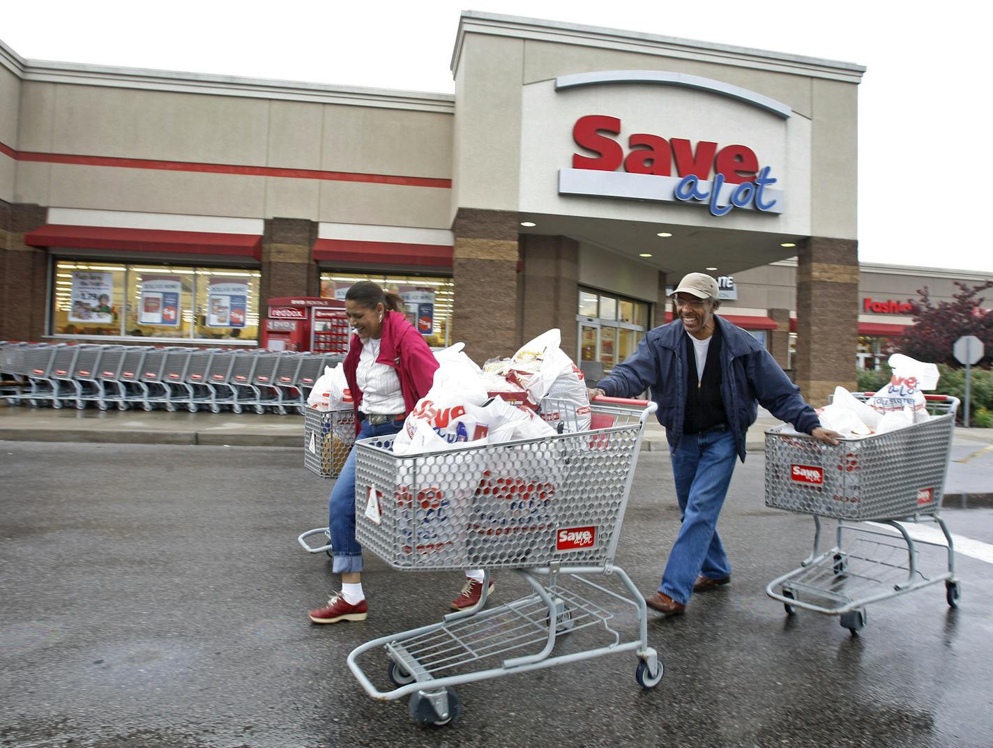 Shoppers Camelious Thompson and her brother Mark Eaton leave a Save-A-Lot store in St. Louis, Missouri, U.S., on Thursday, May 20, 2010. Supervalu Inc.'s Save-A-Lot unit, a discount grocer specializing in store-brand products, plans to expand in urban areas to fill in gaps left after larger chains moved to the suburbs. Photographer: Peter Newcomb/Bloomberg *** Local Caption *** Camelious Thompson; Mark Eaton ORG XMIT: MIN2012120516120005