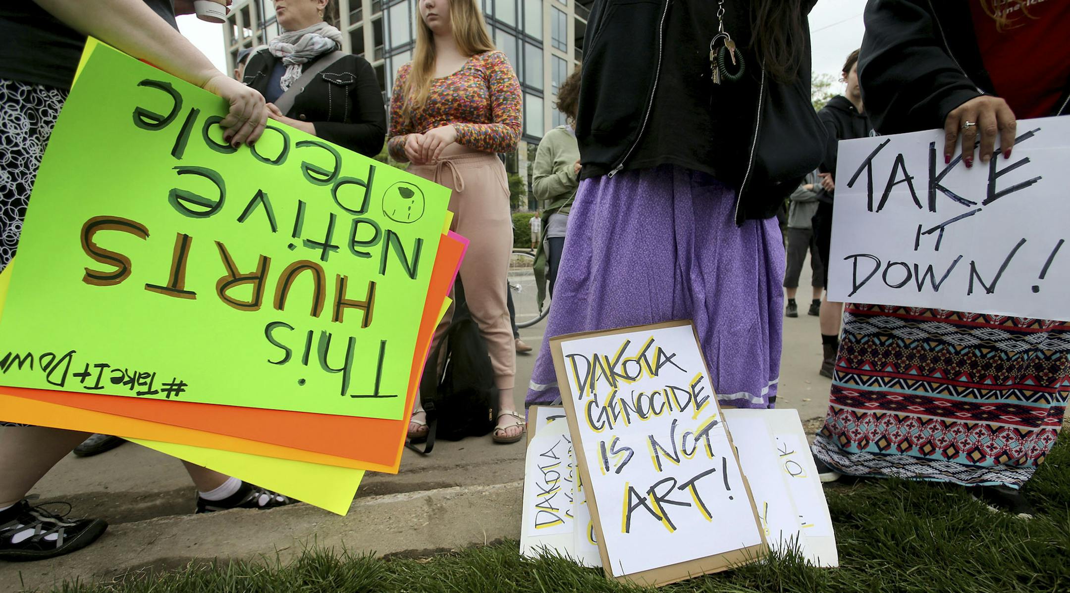Protestors with signs gather outside the Walker Sculpture Garden Saturday, May 27, 2017, in Minneapolis. The Walker Art Center in Minneapolis said Saturday it will remove "Scaffold," a two-story sculpture from 2012 by Los Angeles artist Sam Duranta, because of protests from Native Americans who say it brought back painful memories of the mass hanging of 38 Dakota men in 1862. (David Joles/Star Tribune via AP) ORG XMIT: MIN2017053012145830