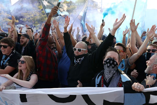 Minnesota United fans sing songs and burn blue smoke bombs as they march into TCF Bank Stadium in Minneapolis before a game against the Philadelphia U