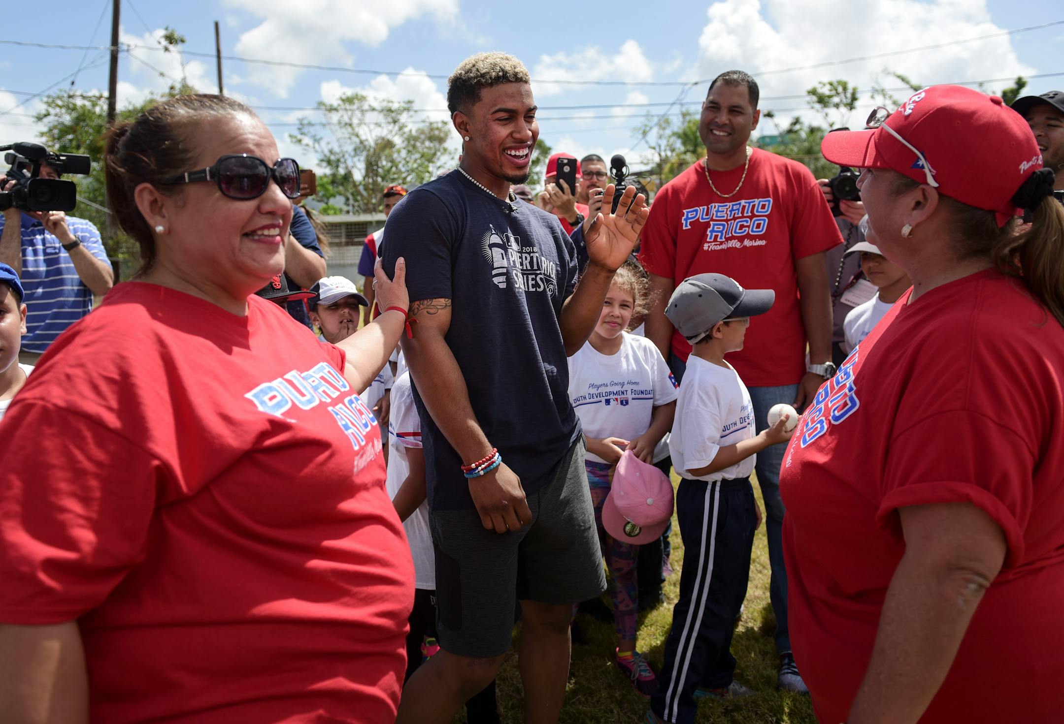 School teachers Norma Torres, right, and Evelyn Hernandez, greet Cleveland Indians All-Star shortstop Francisco Lindor, how visited his former grammar school, Villa Marina Elementary School, to lead a special baseball clinic for approximately 250 students in Gurabo, Puerto Rico, Monday, April 16, 2018. Next Tuesday and Wednesday, the Cleveland Indians and the Minnesota Twins will meet in a two-game series at Hiram Bithorn Stadium in San Juan. (AP Photo/Carlos Giusti)