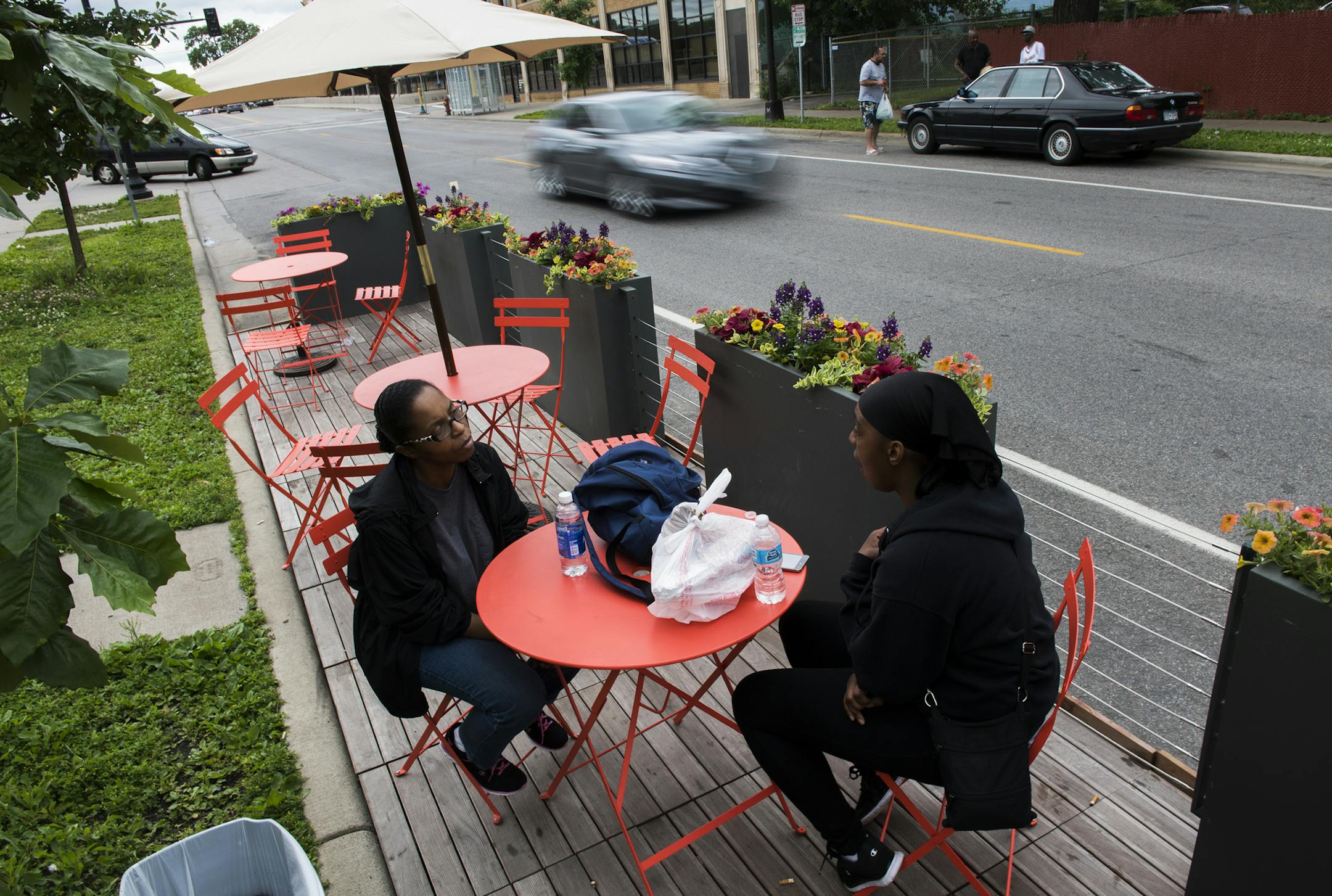 Inez Howard, left, talks with her daughter Shanay Ponder at the new parklet seating outside of Twin Cities Coffee and Deli on Chicago Ave. on Wednesday. "This is the first time I've seen it," said Ponder of the new seating. "I love it." ] Isaac Hale ï isaac.hale@startribune.com The city is expanding its Parklet program to include "street cafes", pop-up spaces to eat in curbside parking spots outside restaurants.
