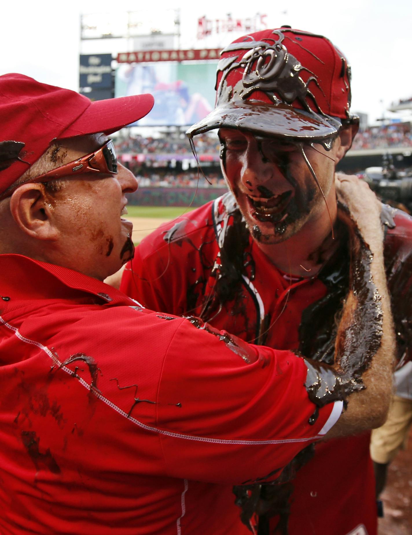 Washington Nationals owner Mark Lerner, left, embraces Washington Nationals starting pitcher Max Scherzer, who is covered with chocolate syrup, after Scherzer's no-hitter baseball game against the Pittsburgh Pirates at Nationals Park, Saturday, June 20, 2015, in Washington. The Nationals won 6-0. (AP Photo/Alex Brandon)