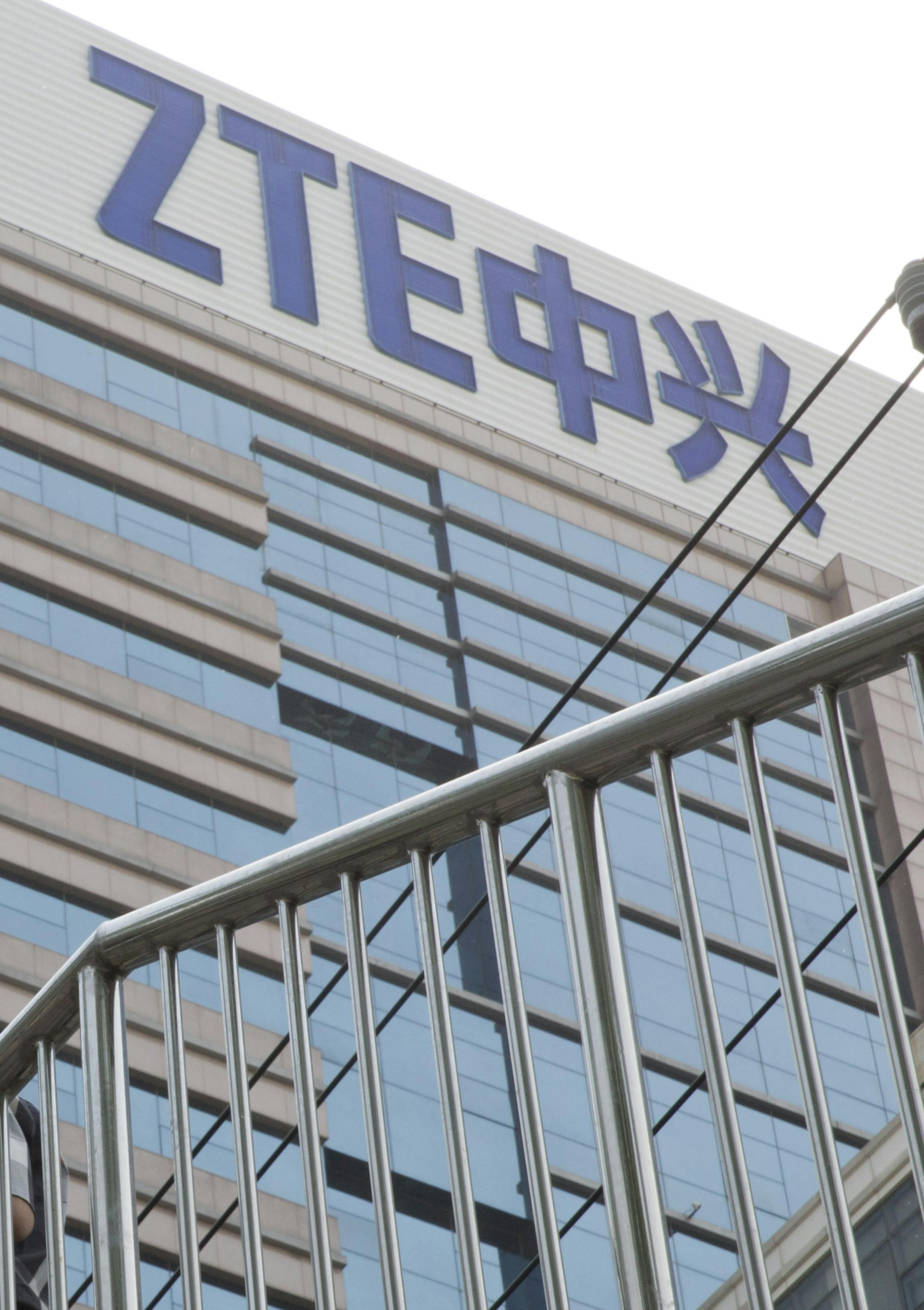 In this May 8, 2018, photo, Chinese men pass by a ZTE building in Beijing, China. President Donald Trump's weekend social media musings about China injected new uncertainty into the Washington's punishment of Chinese tech giant ZTE and planned trade talks between the two countries. (AP Photo/Ng Han Guan) ORG XMIT: XHG101