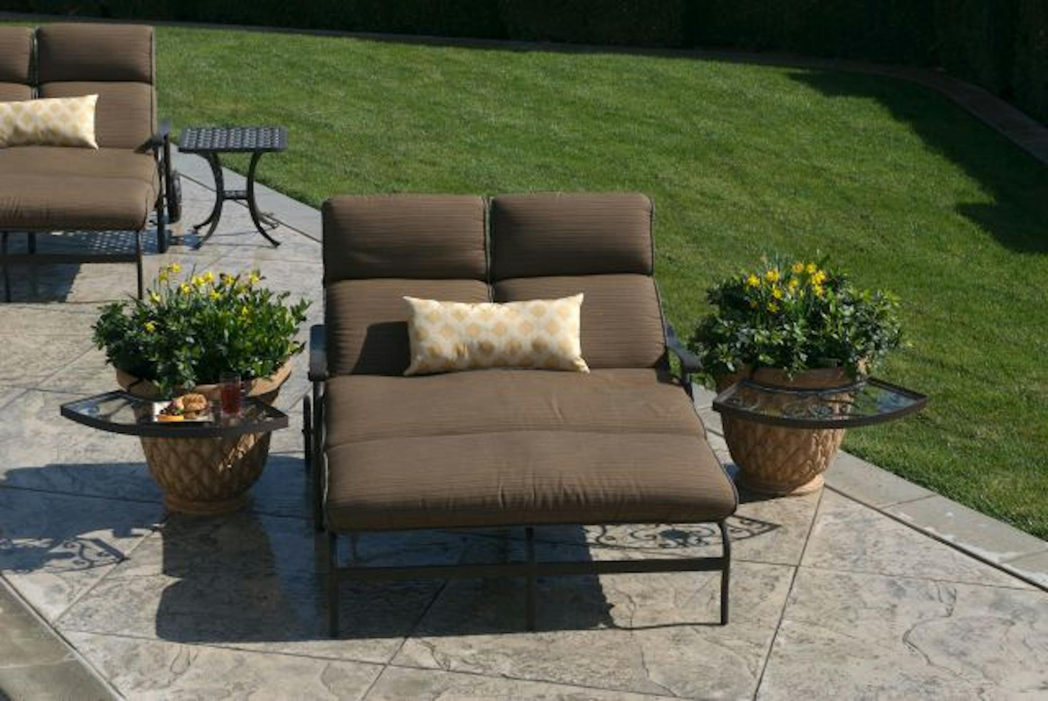 "The Ledge," an iron and glass structure functions as a legless end table by slipping on to pots, urns and ground planters to provide a resting spot for drinks and other items.