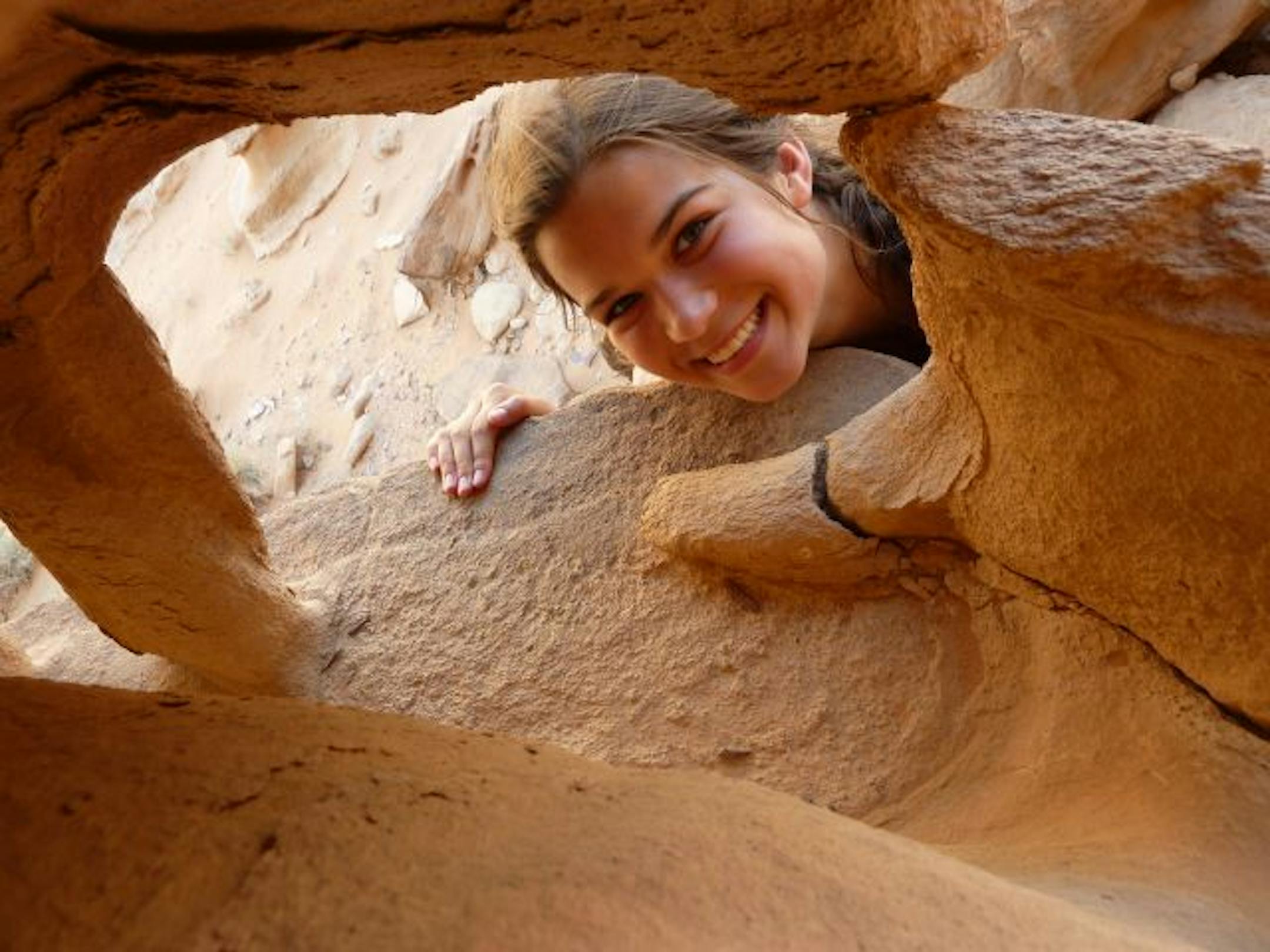 Becca Ebert peers through a hole in weathered stone in the wadi Rum desert of Jordan.