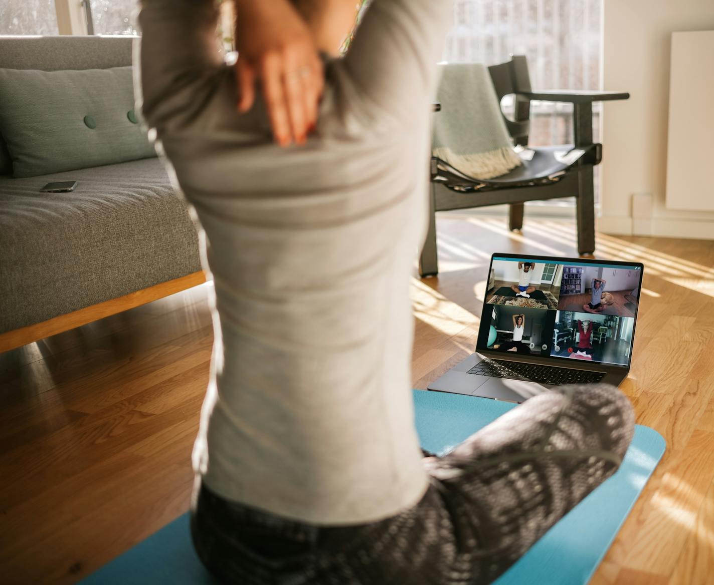 Fitness coach teaching yoga online to group of people. Yoga trainer demonstrating yoga poses to students via video conference.