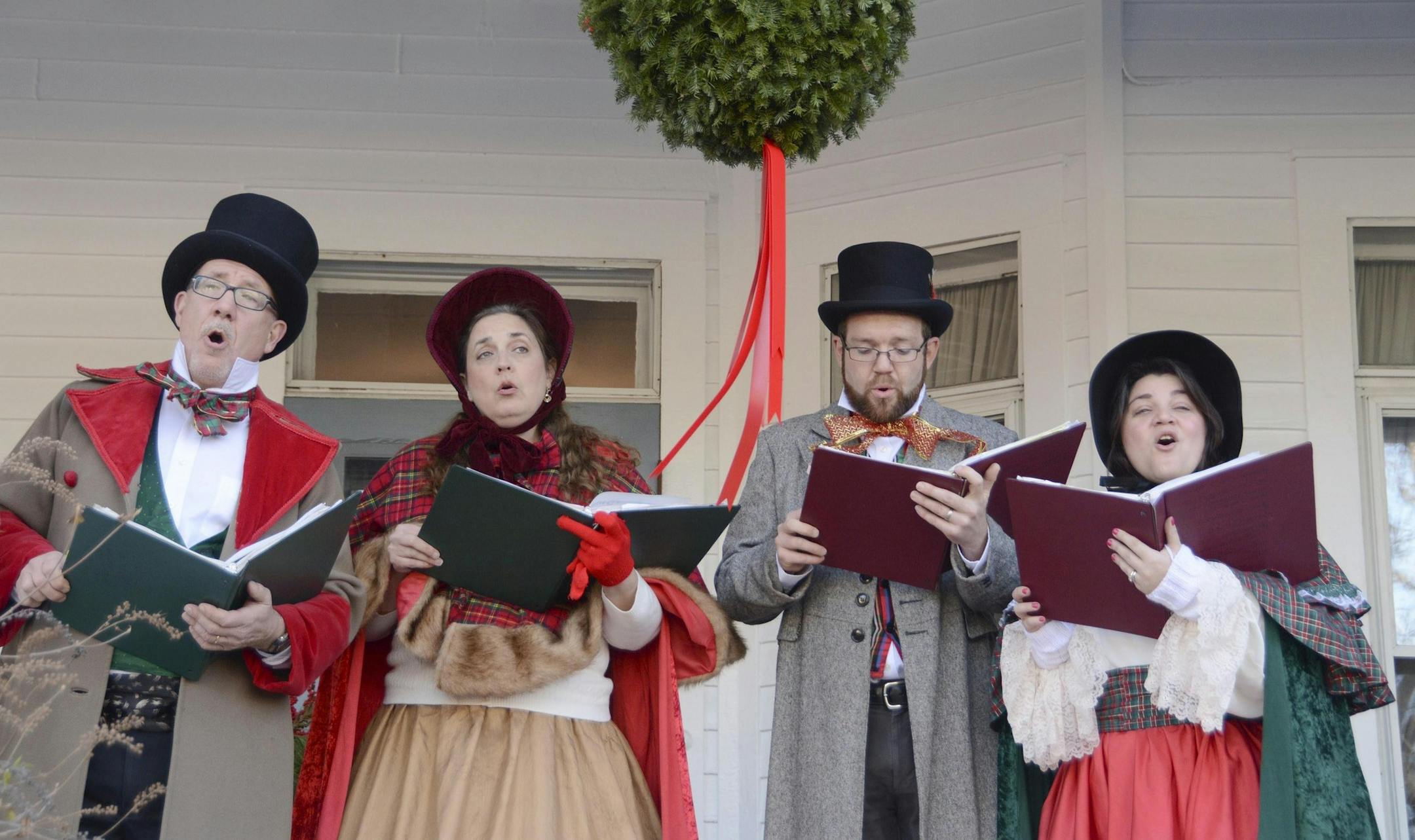 From left, John and Kara Demler, Matt and Jessica Passetto, who are known as The London Town Carolers of Pittsfield, Mass. sing holiday songs from the porch of The Red Lion Inn in Stockbridge, Mass. during the town's annual 'Home for the Holidays' event which pays homage to Norman Rockwell's 'Stockbridge Main Street at Christmas.' Sunday, Dec. 4, 2016. (Gillian Jones,/he Berkshire Eagle via AP)