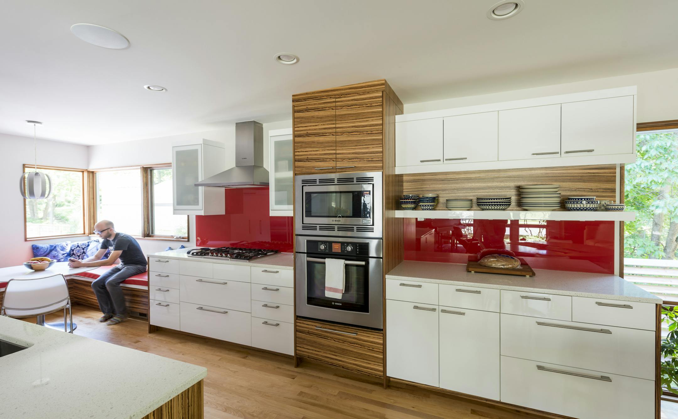 Some of the high-gloss Ikea kitchen cabinets are accented with custom zebrawood doors; the backsplash is back-painted glass.