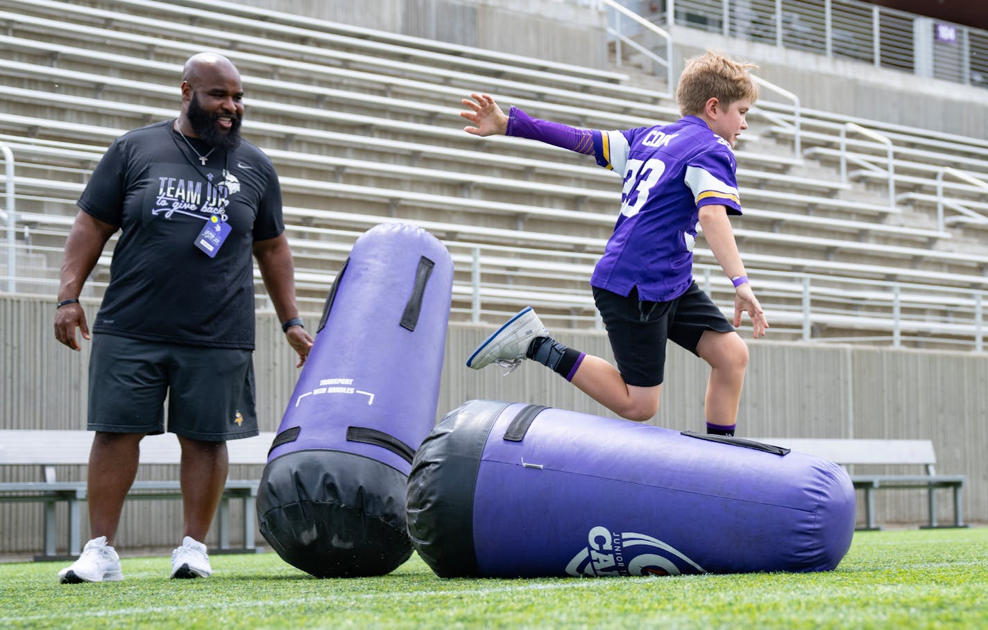 Levi Howes runs through an obstacle course in front of Minnesota Vikings assistant defensive line coach Patrick Hill during a volunteer community event Thursday, June 1, 2023, at TCO Performance Center in Eagan, MN. ]