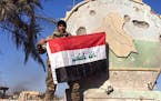 An Iraqi soldier holds a national flag in the government complex in central Ramadi, 70 miles (115 kilometers) west of Baghdad, Iraq, Monday, Dec. 28, 