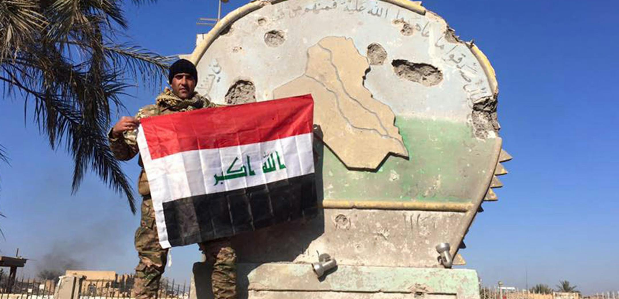 An Iraqi soldier holds a national flag in the government complex in central Ramadi, 70 miles (115 kilometers) west of Baghdad, Iraq, Monday, Dec. 28, 2015. Iraqi military forces on Monday retook a strategic government complex in the city of Ramadi from Islamic State militants who have occupied the city since May. (AP Photo) ORG XMIT: MIN2015123014233375