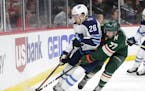 Winnipeg Jets forward Jack Roslovic (28) controls the puck in front of Minnesota Wild defenseman Brad Hunt (77) in the first period of an NHL hockey g