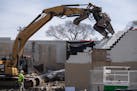 An excavator begins the demolition work of the former O'Reilly Auto Parts store on Lake Street, which was destroyed in the riots following George Floy