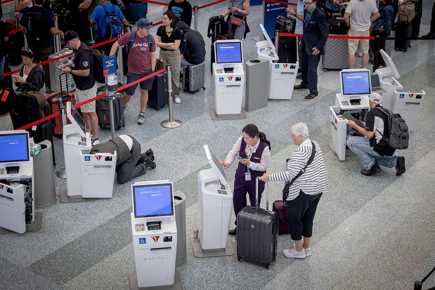 Delta Airlines employees work on self-service kiosks Friday as passengers flood the area at Minneapolis-St. Paul International Airport.