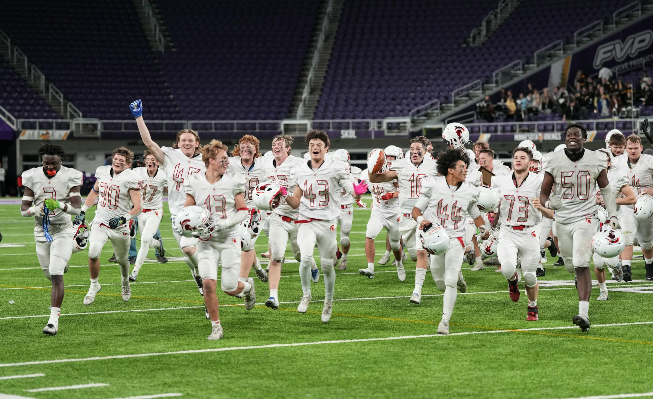 Simley Spartans teammates run to celebrate with the fan section at the end of the game.