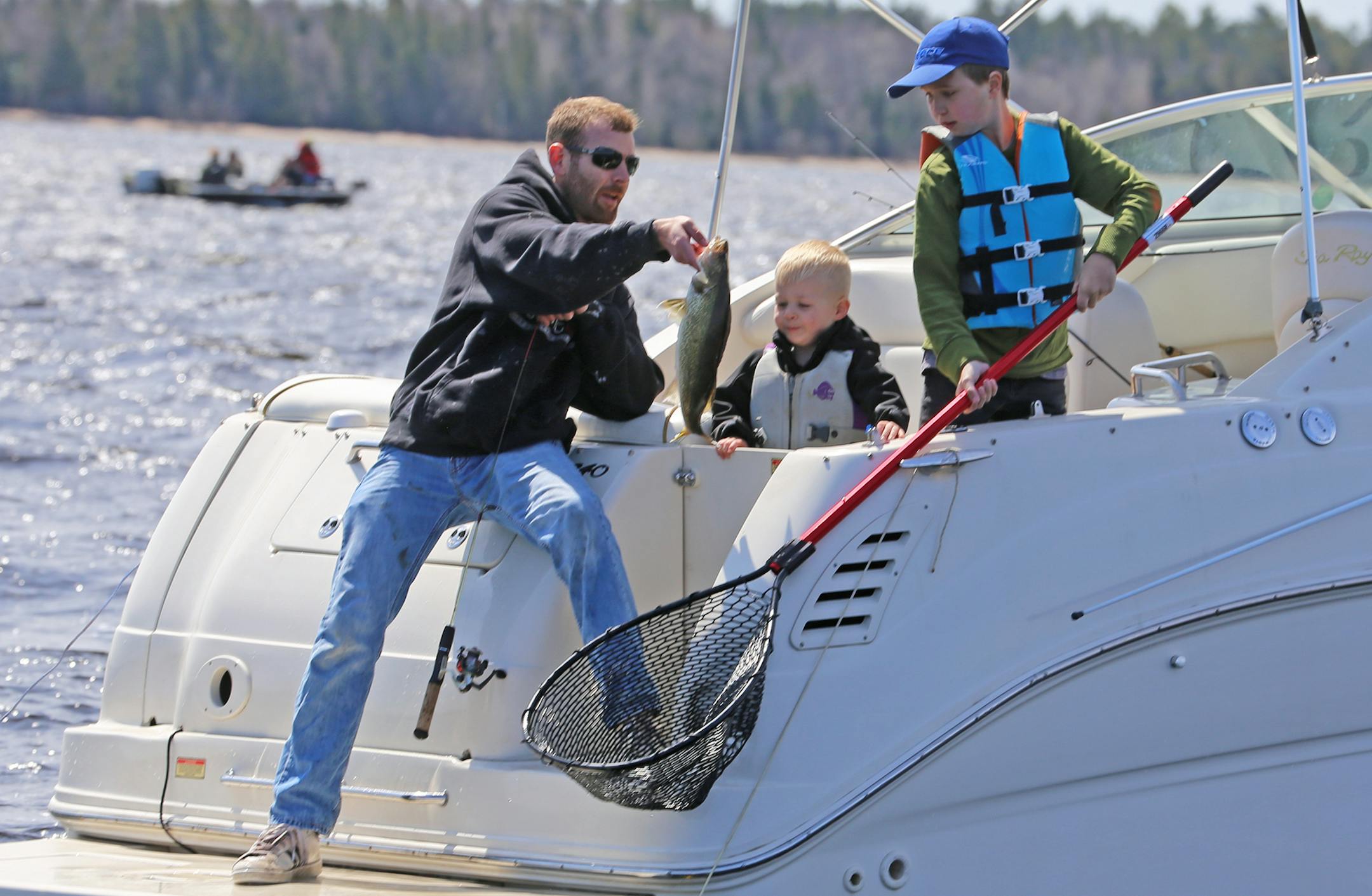 Catching walleyes was a family activity Saturday for Aaron Hobbs, who presented his catch to 3-year-old son Erik while Graden Harms, 10, manned the net.