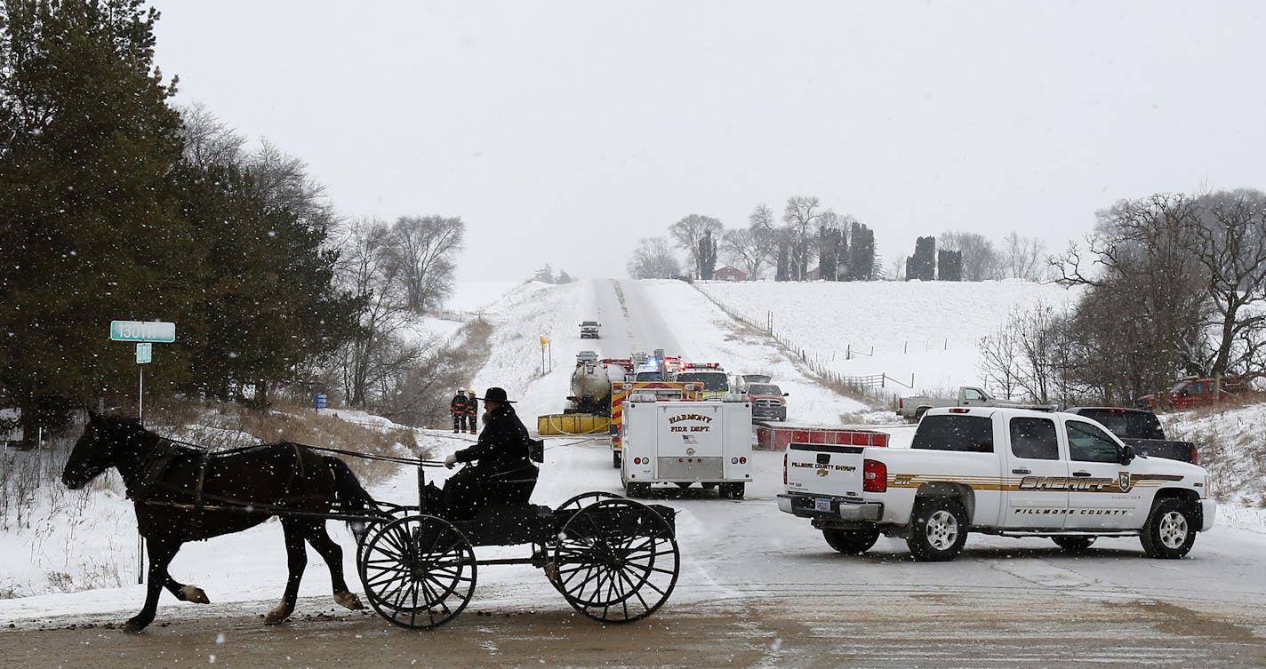 An Amish man crosses County Road 21 at 130th Street while emergency vehicles block the road for a fire at the Yost Hershberger property Monday, Jan. 11, 2016, near Canton, Minn. Firefighters were searching for two missing people after a fire started in the early morning. (Andrew Link/Rochester Post-Bulletin via AP)