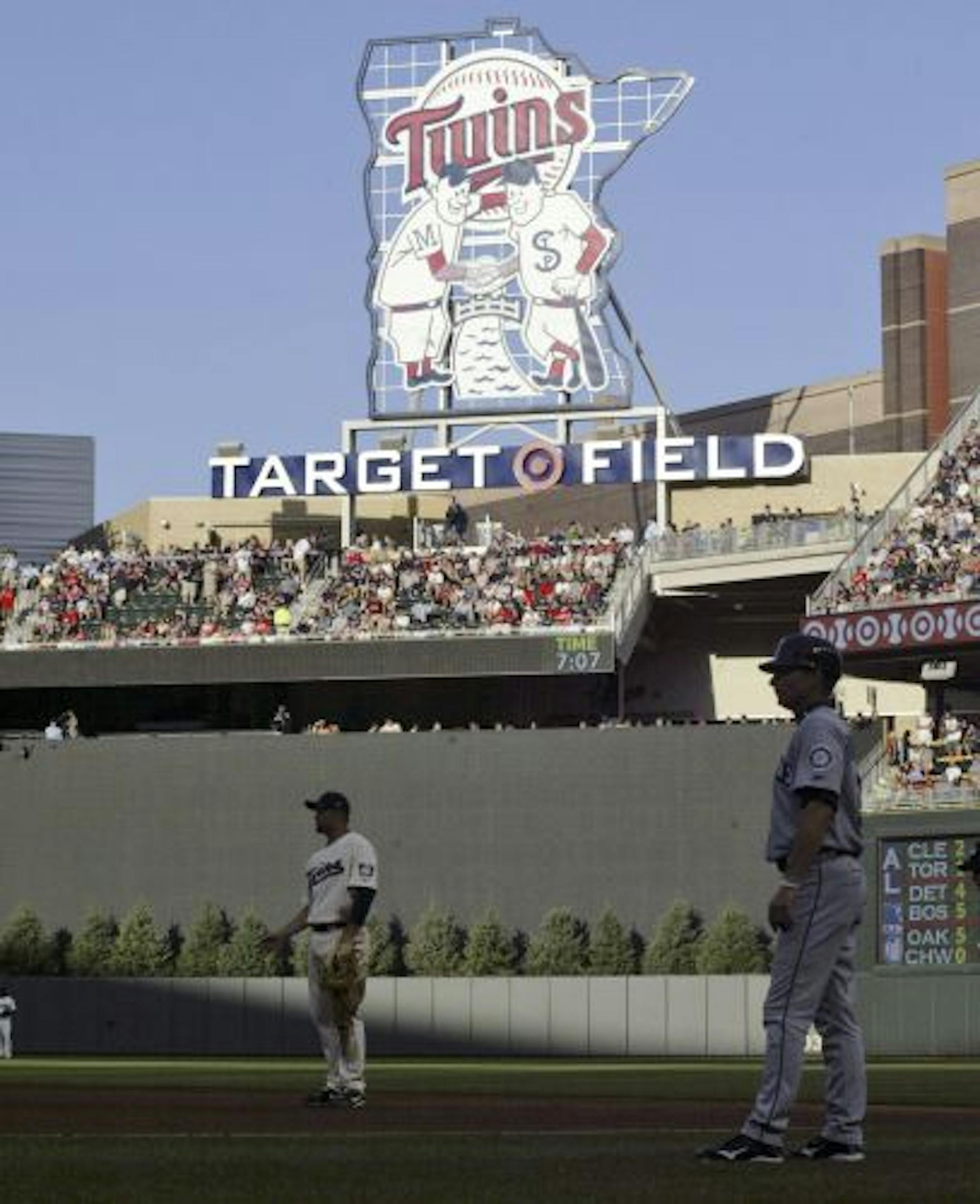 FILE- In this July 31, 2010, file photo, the center field sign Target Field featuring the Minnie and Paul logo looms over the field during a baseball game between the Minnesota Twins and the Seattle Mariners in Minneapolis. The Twins said they will take down the pine trees behind center field wall after hitters complained they made it difficult for them to pick up the ball out of the pitcher's hand.