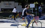 In this Oct. 20, 2015 photo, employees ride company bicycles outside Google headquarters in Mountain View, Calif. (AP Photo/Marcio Jose Sanchez) ORG X