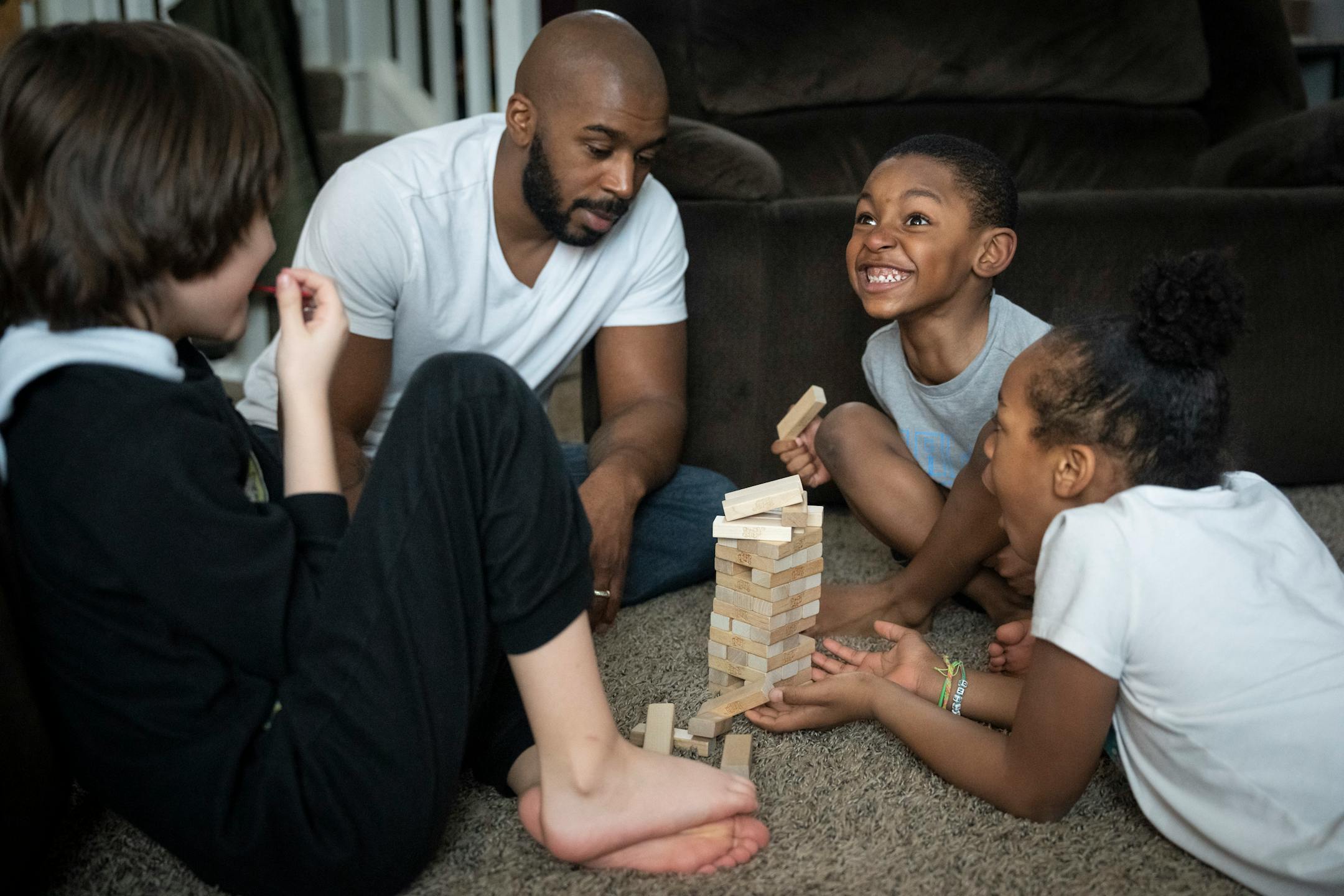 Deonté Haynes plays Jenga with his three younger children (from the left) Alex, 8, Deonté Jr., 6, and Jalei, 8, after he took the day off from work so he could help with distance learning during the snow storm while his wife Ja'Mira works in their home office.