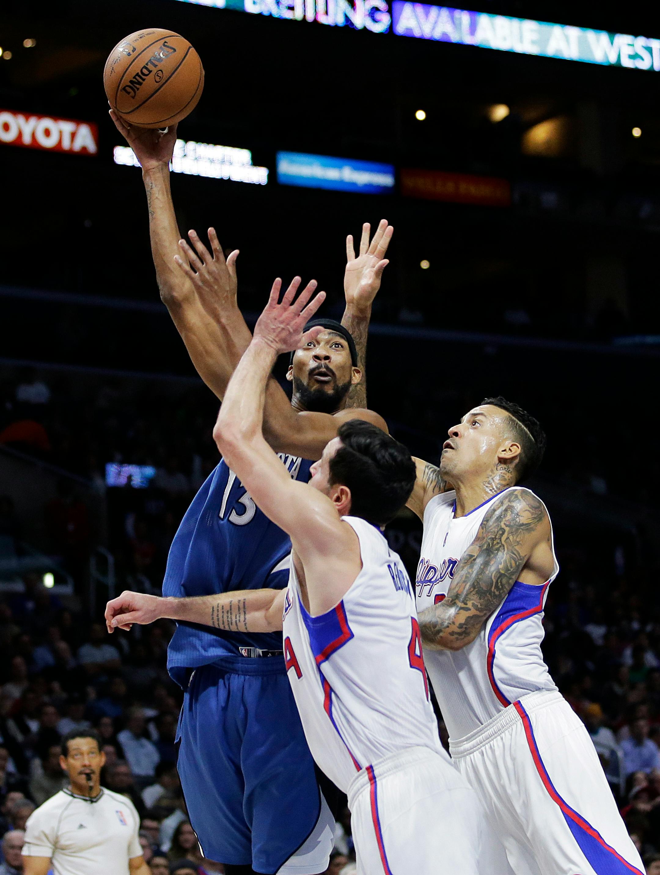 Minnesota Timberwolves' Corey Brewer, top, shoots as he is defended by Los Angeles Clippers' J.J. Redick, center, and Matt Barnes during the first half of an NBA basketball game Monday, Dec. 1, 2014, in Los Angeles. (AP Photo/Jae C. Hong)