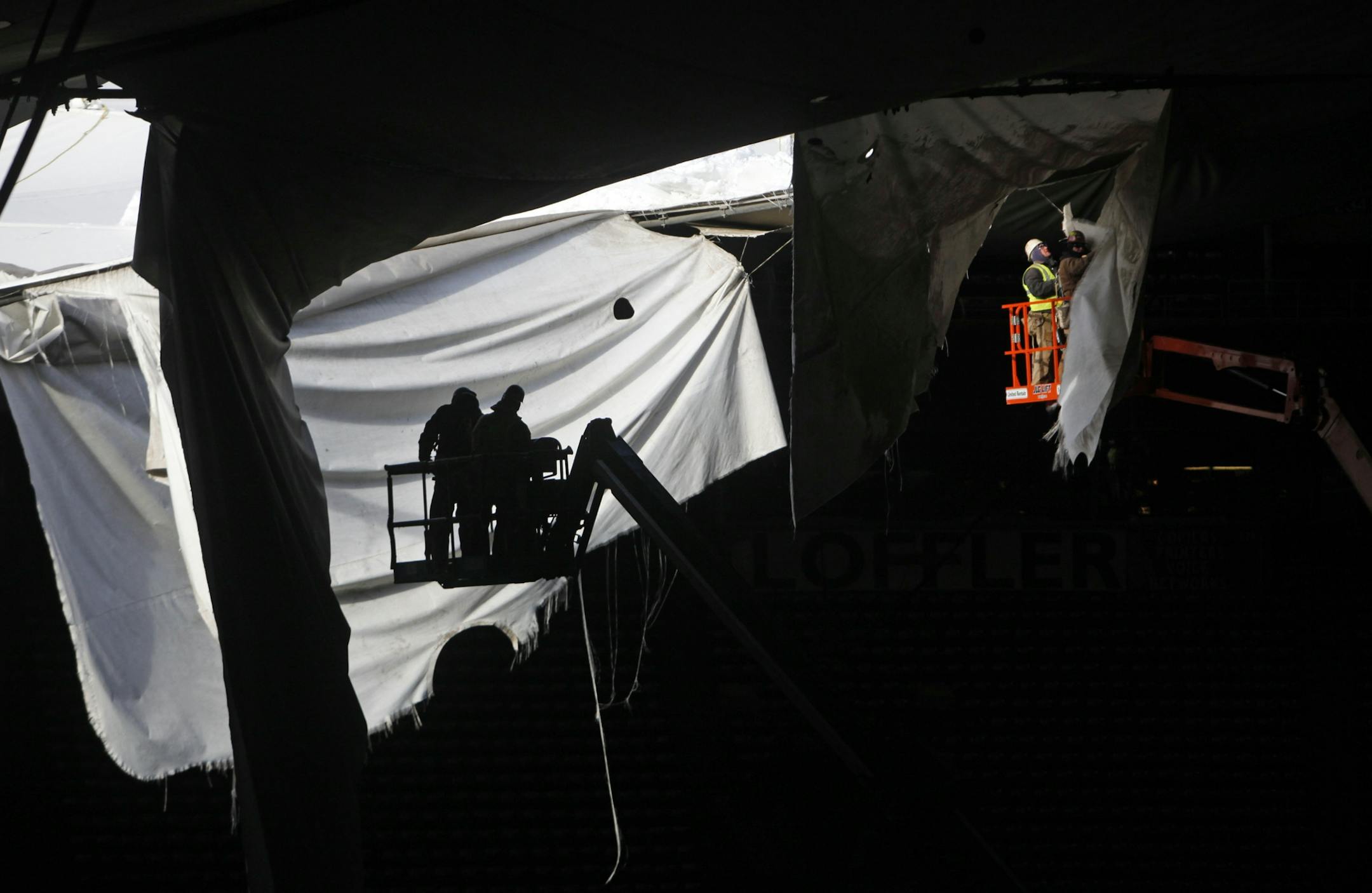 Workers inspect tears to the roof before they are cut down.
