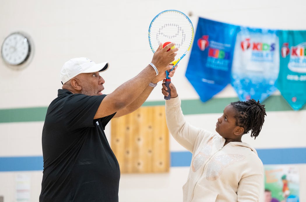Tennis professional Neil Hill teaches Harlem Davis proper technique on an overhead swing during a InnerCity Tennis-led physical education class at Bryn Mawr Elementary School in Minneapolis on Tuesday.