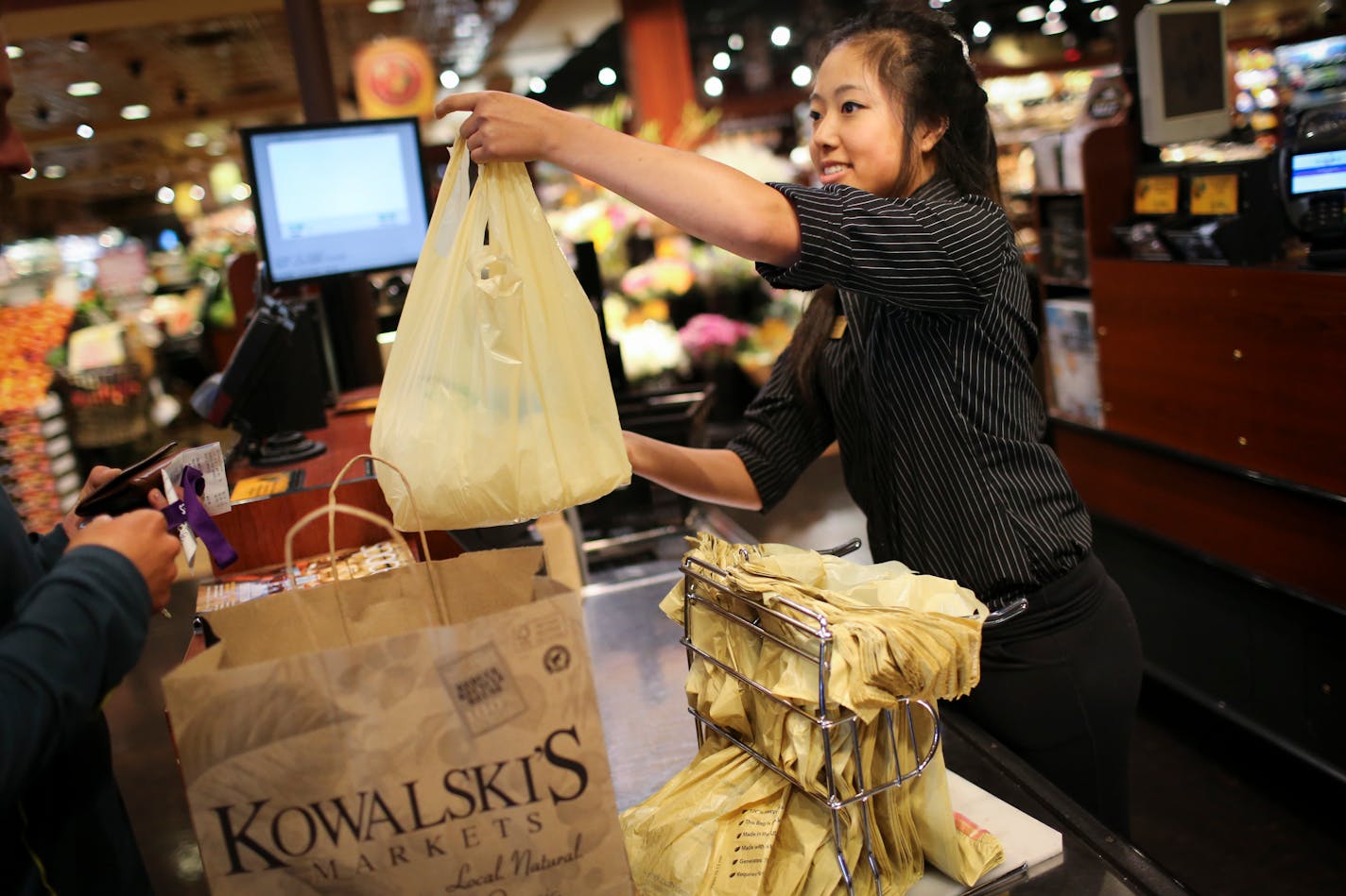 Hannah Peterson handed a plastic bag of groceries to a customer at Kowalski's in Uptown in Minneapolis, Minn., on Thursday, July 23, 2015. ] RENEE JONES SCHNEIDER � reneejones@startribune.com