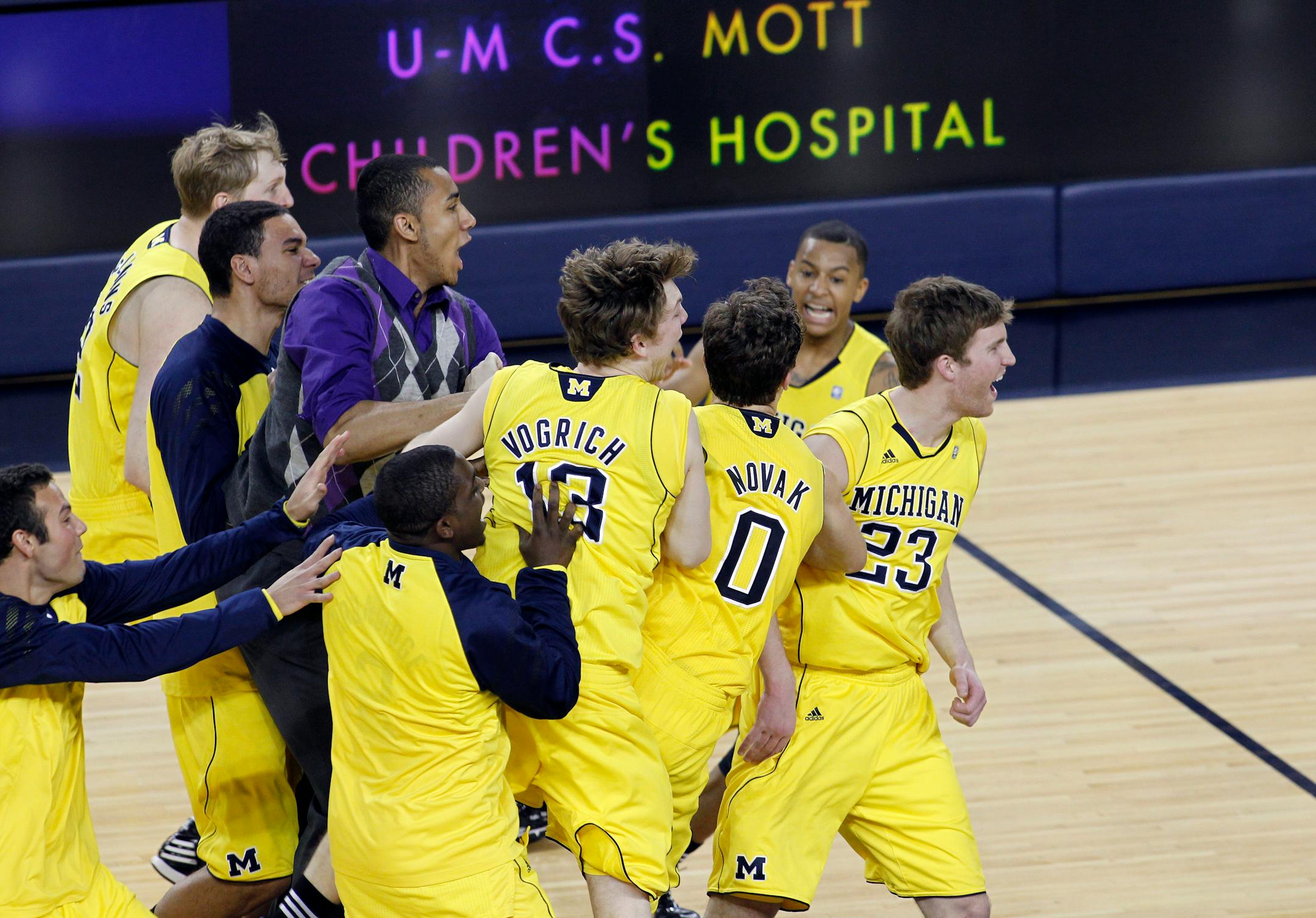 Michigan players Matt Vogrich, Zack Novak, and Evan Smotrycz were mobbed by teammates in celebration after the Wolverines' 60-59 victory over Michigan State on Tuesday night in Ann Arbor.