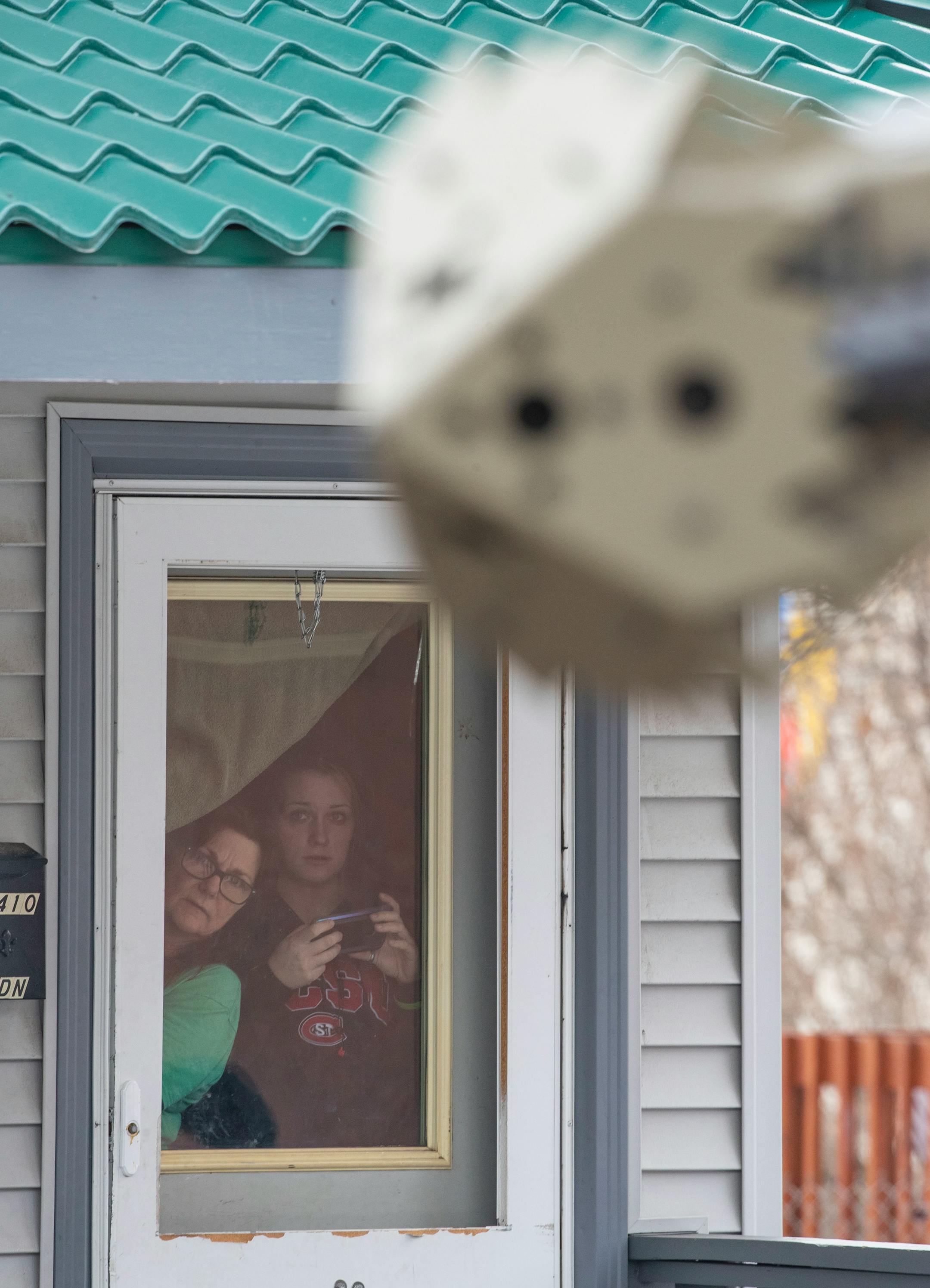 Local neighbors tried to get a look at the scene outside as St. Louis County sheriffs worked to assemble a grenade launcher to send non-lethal smoke grenades into the suspect's home. ]