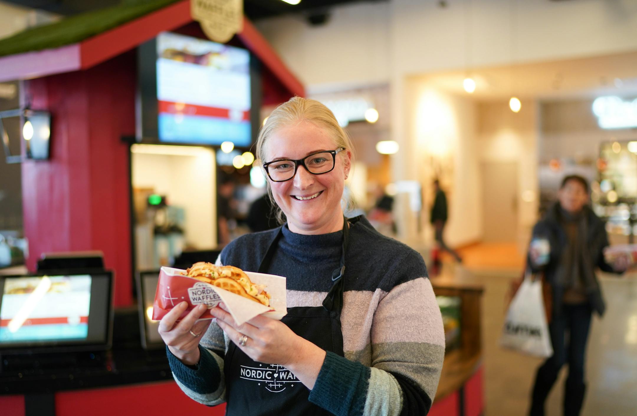 Nordic Waffles owner Stine Aasland held a Bacon, Mac &amp; Cheese waffle at her stand which is inside Rosedale Mall's new food hall, Potluck. ] GLEN STUBBE • glen.stubbe@startribune.com Thursday, December 12, 2019 Restaurant trend: Food halls. Nordic Waffles owner Stine Aasland runs a stand just inside the mall entrance in Potluck,