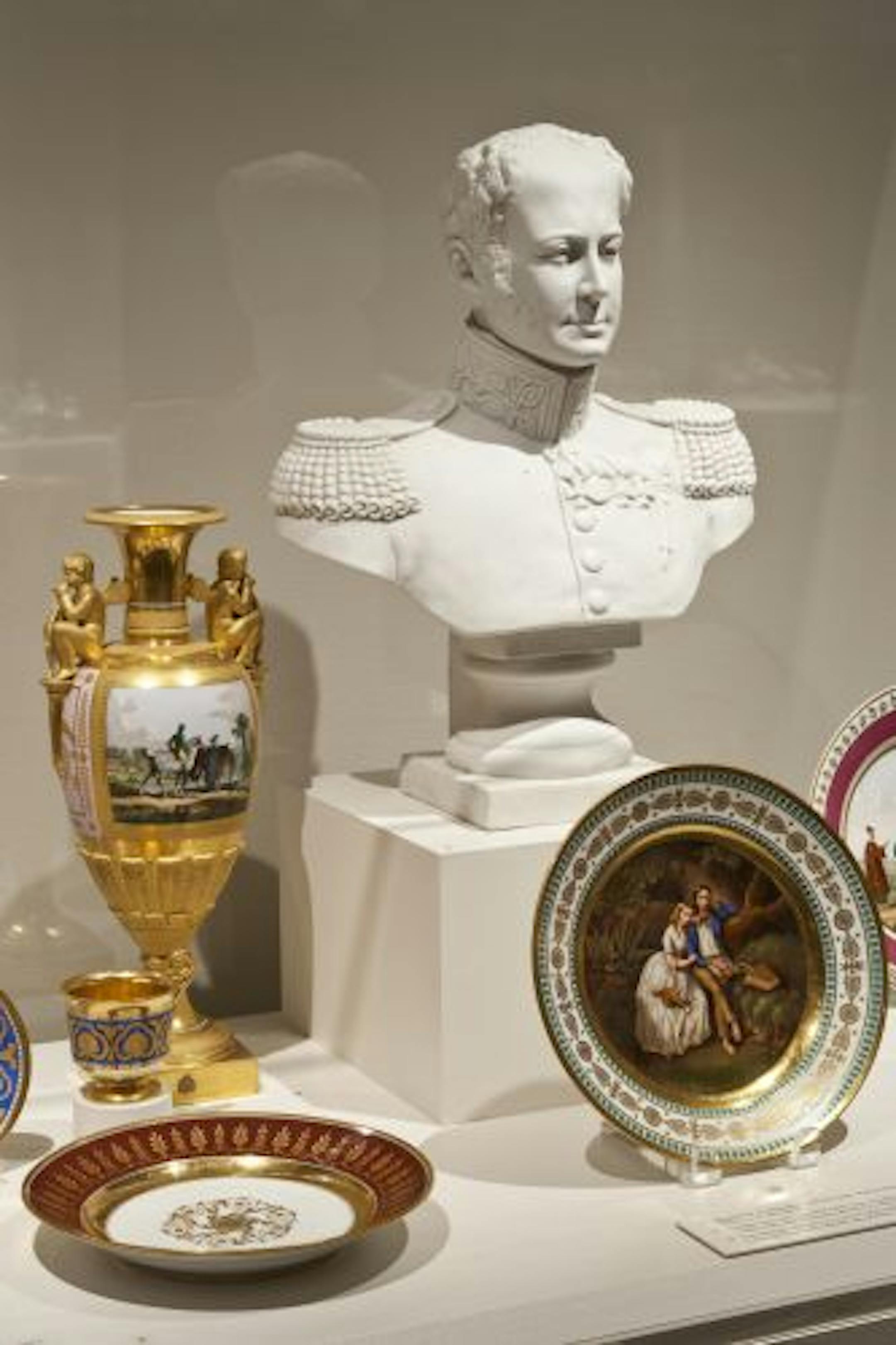 An unglazed bust of Tsar Alexander I, whose armies outwitted Napoleon, overlooks porcelain from his reign (1801-25). A plate features a Russian picnic; the vase depicts a country estate.