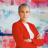 A woman in a red blazer is photographed in front of a modern art canvas.