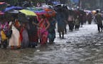 People wade through a waterlogged street during monsoon rains in Mumbai, India, Monday, July 1, 2019. India's monsoon season runs from June to Septemb