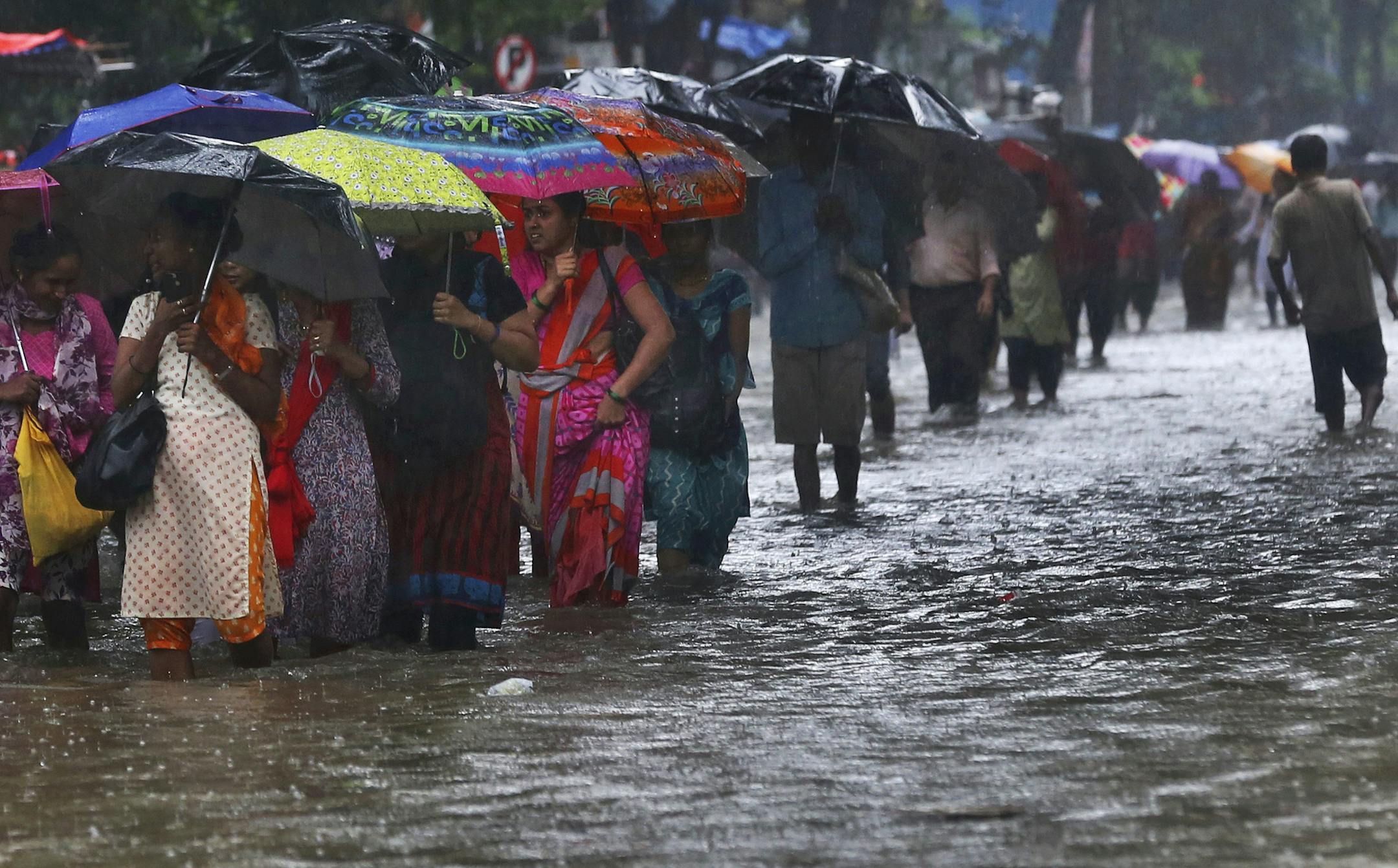 People wade through a waterlogged street during monsoon rains in Mumbai, India, Monday, July 1, 2019. India's monsoon season runs from June to September. (AP Photo/Rafiq Maqbool)
