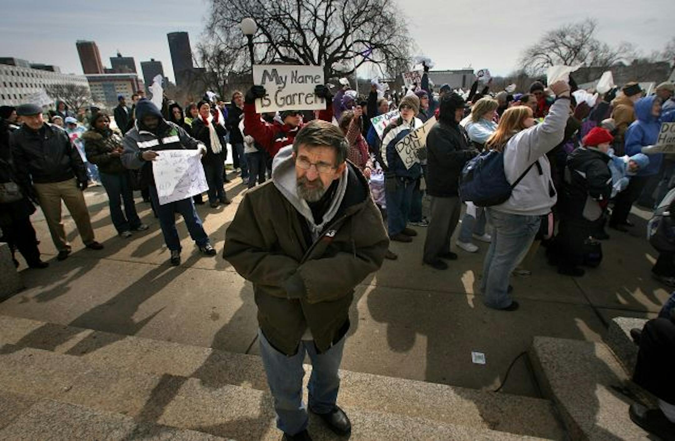Larry Goetzinger, Caledonia, 61, warmed his hands in his sleeves as he listened to speakers at a protest to budget cuts to people with disabilities and older Minnesotans Saturday at the State Capitol.