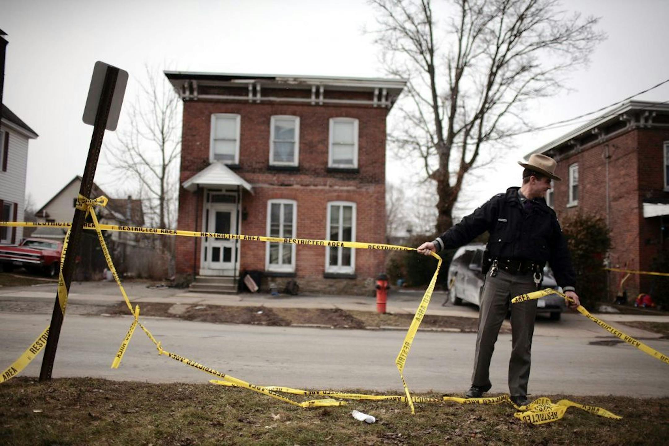 A police officer puts tape outside the home of shooting suspect Kurt Myers in Mohawk, N.Y., March 14, 2013. An overnight standoff between the police and Myers, who suspected of two shootings on Wednesday that killed four and injured two others, came to an end early Thursday when the police stormed a building where he was holed up and killed him in an exchange of gunfire.