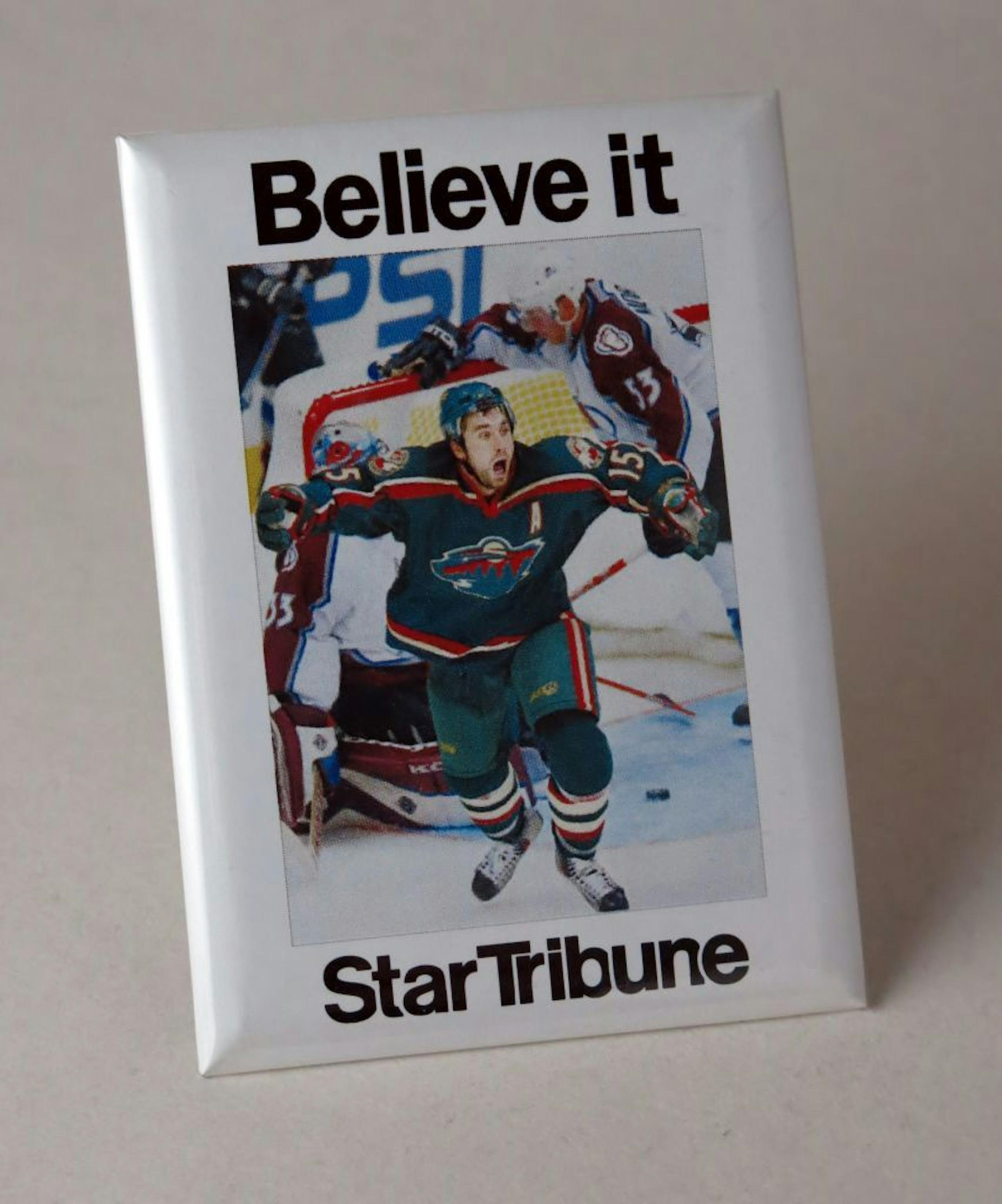 The Star Tribune made laminated photo 'pins' showing Brian Peterson's photo of the game winning goal by Mn Wild Andrew Brunette in game 7 of the 2003 playoffs.