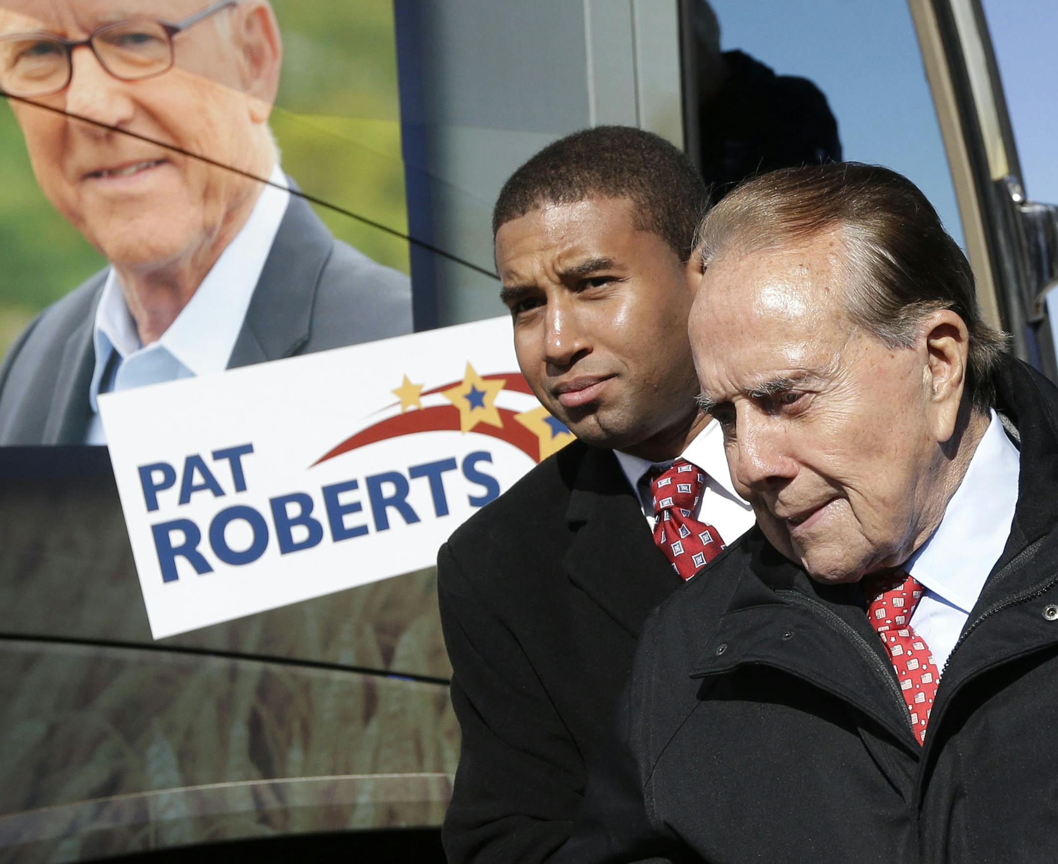 Former Sen. Bob Dole, R-Kan., is helped to his position during a campaign stop in support of Sen. Pat Roberts and Gov. Sam Brownback in Kansas City, Kan., Friday, Oct. 31, 2014. (AP Photo/Orlin Wagner) ORG XMIT: MIN2014110115243520
