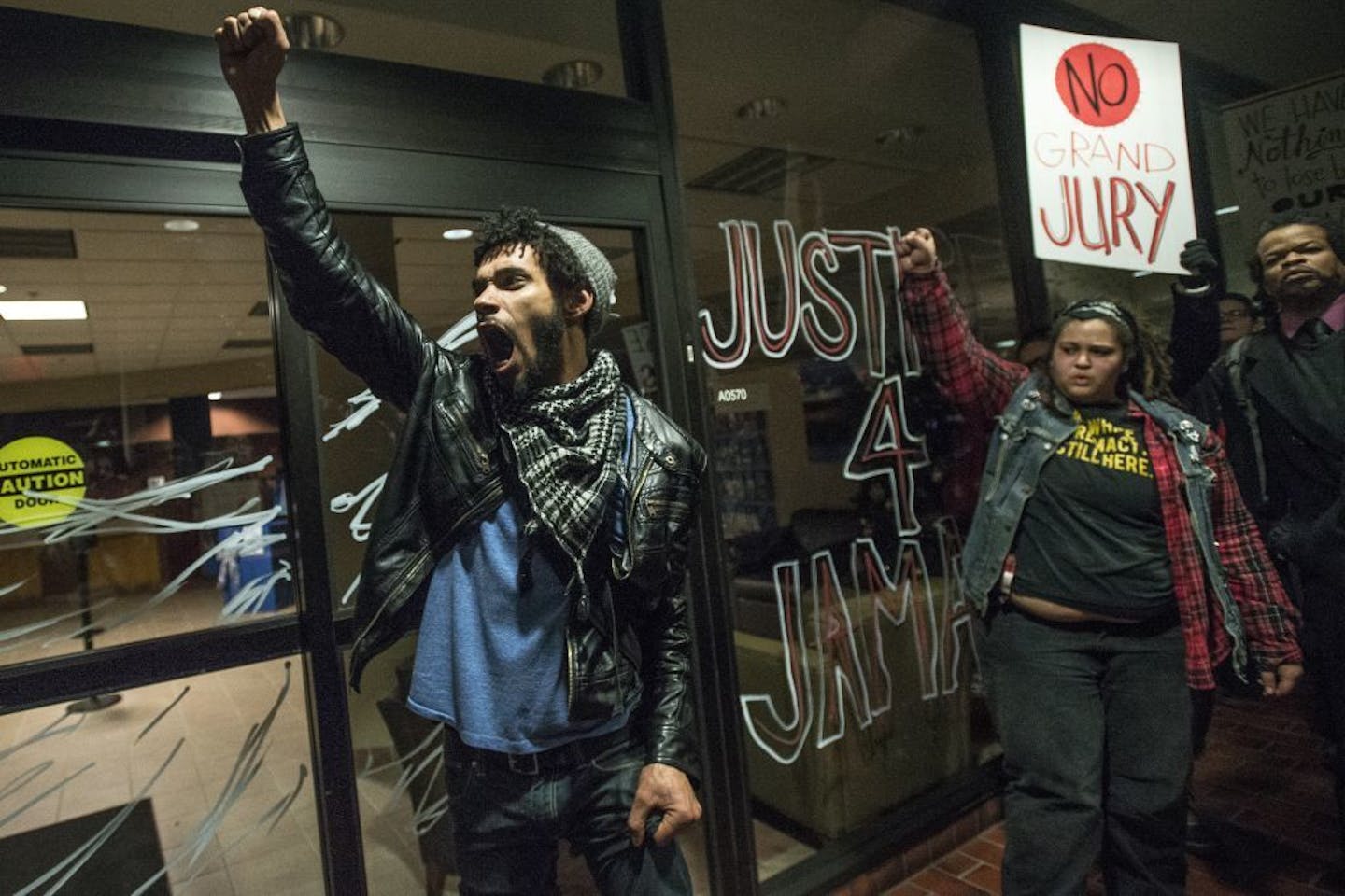 Activist Jacob Ladda chanted with fellow protesters after using a nonpermanent marker to write "Justice 4 Jamar" on the windows of Wings Financial on Thursday night.